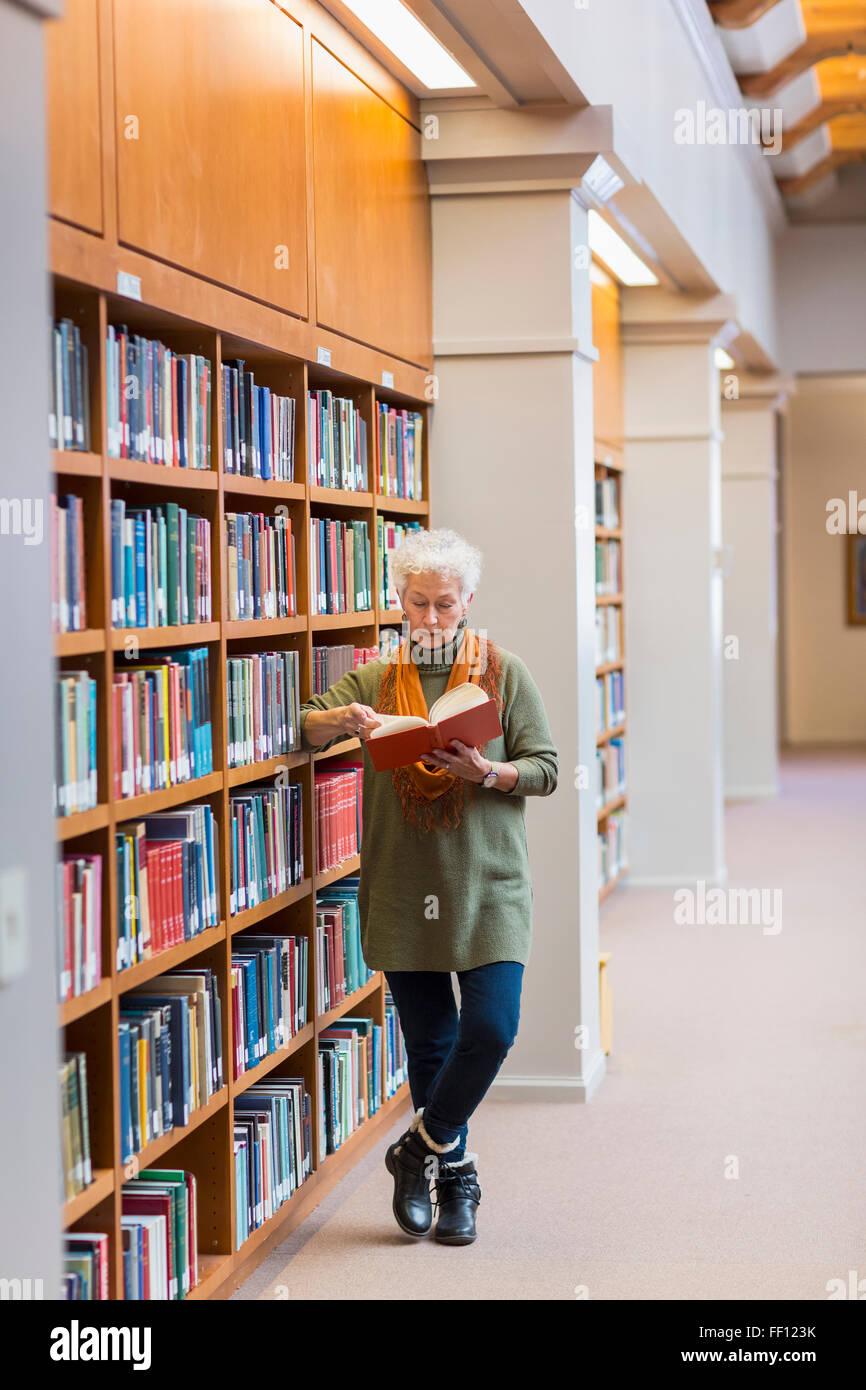 Plus mixed race woman reading book in library Banque D'Images