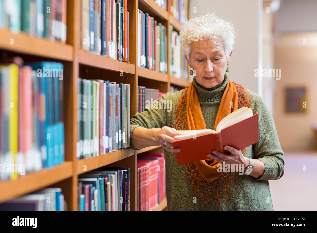 Plus mixed race woman reading book in library Banque D'Images