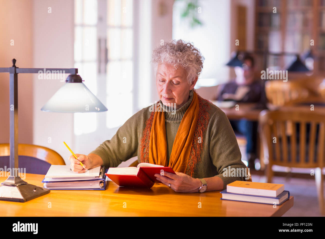 Plus mixed race woman reading book in library Banque D'Images