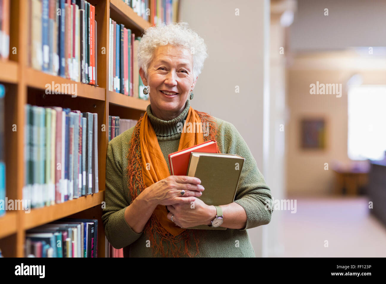 Plus mixed race woman holding books in library Banque D'Images