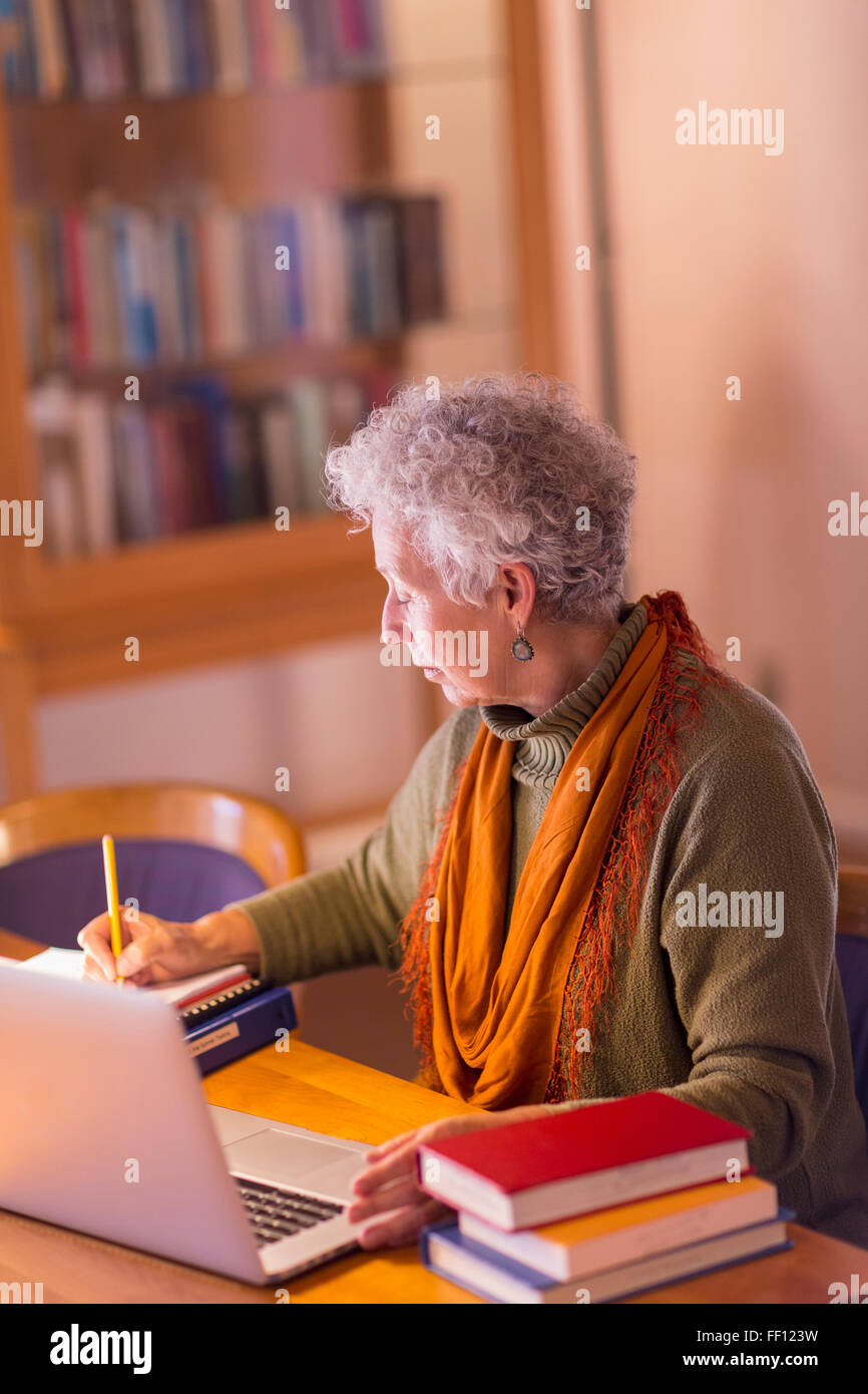 Plus mixed race woman writing in library Banque D'Images