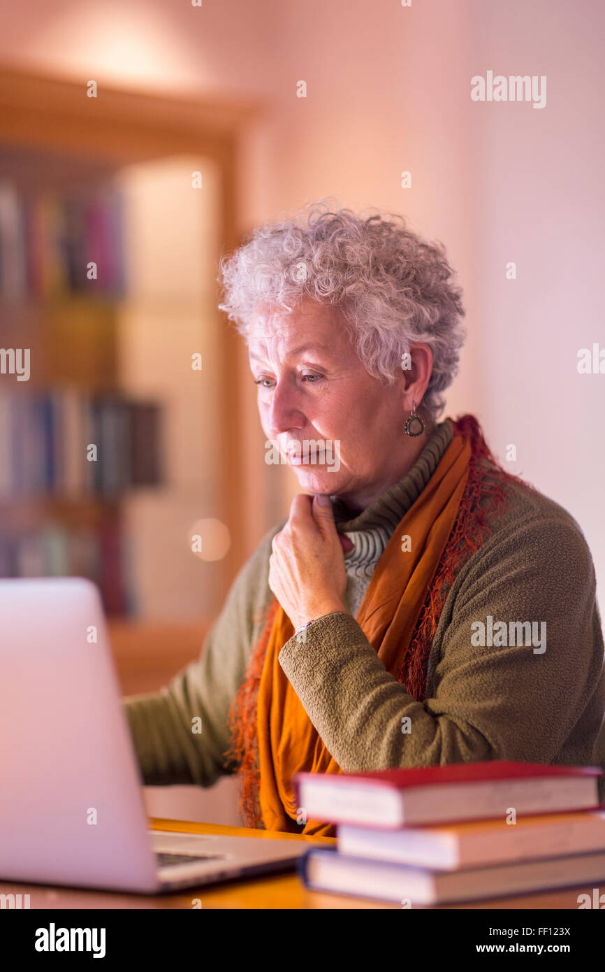 Plus mixed race woman using laptop in library Banque D'Images
