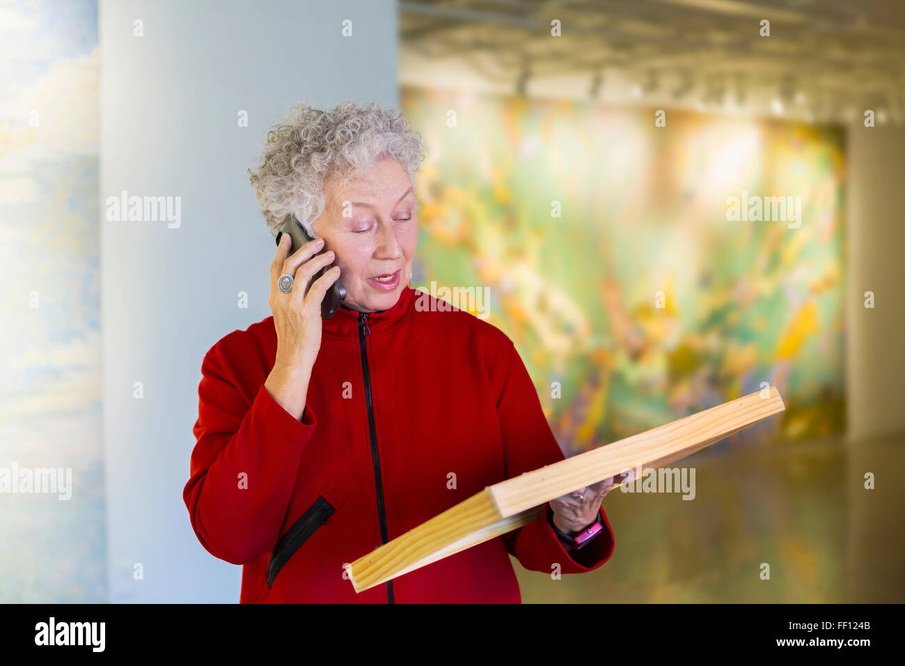 Plus mixed race Woman talking on phone in art gallery Banque D'Images
