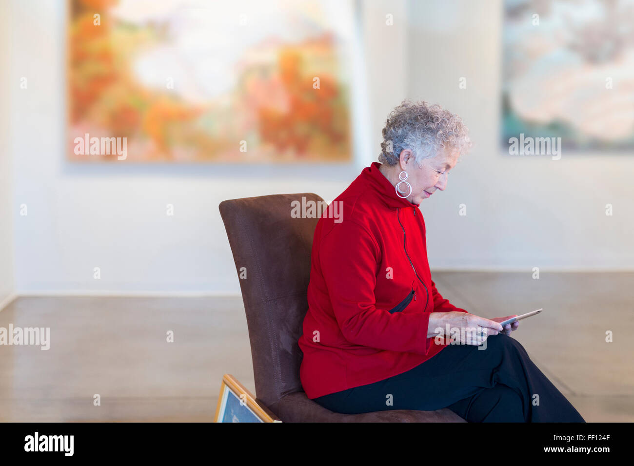 Plus mixed race woman using digital tablet in art gallery Banque D'Images