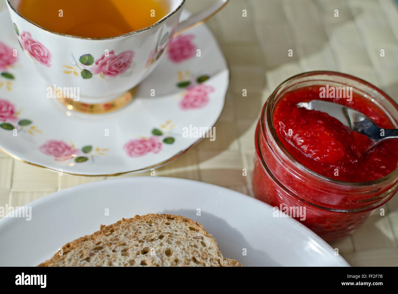Un thé avec du pain et de la confiture. Verre avec pot de confitures faites maison et de Berry tranche de pain multigrains /de grains germés dans une assiette. Banque D'Images
