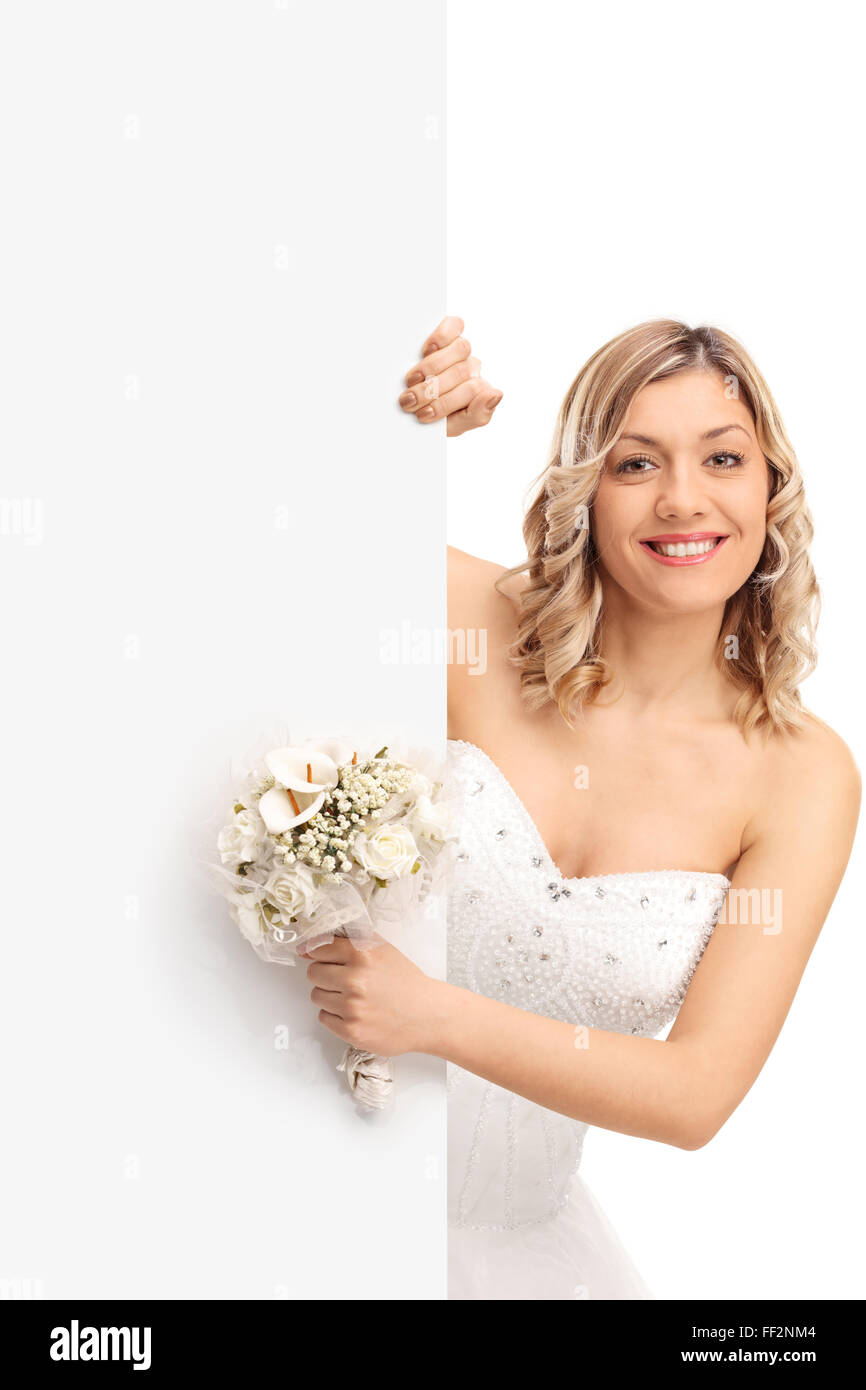 Shot verticale d'une jeune femme tenant une fleur de mariage et debout derrière un panneau blanc isolé sur fond blanc Banque D'Images