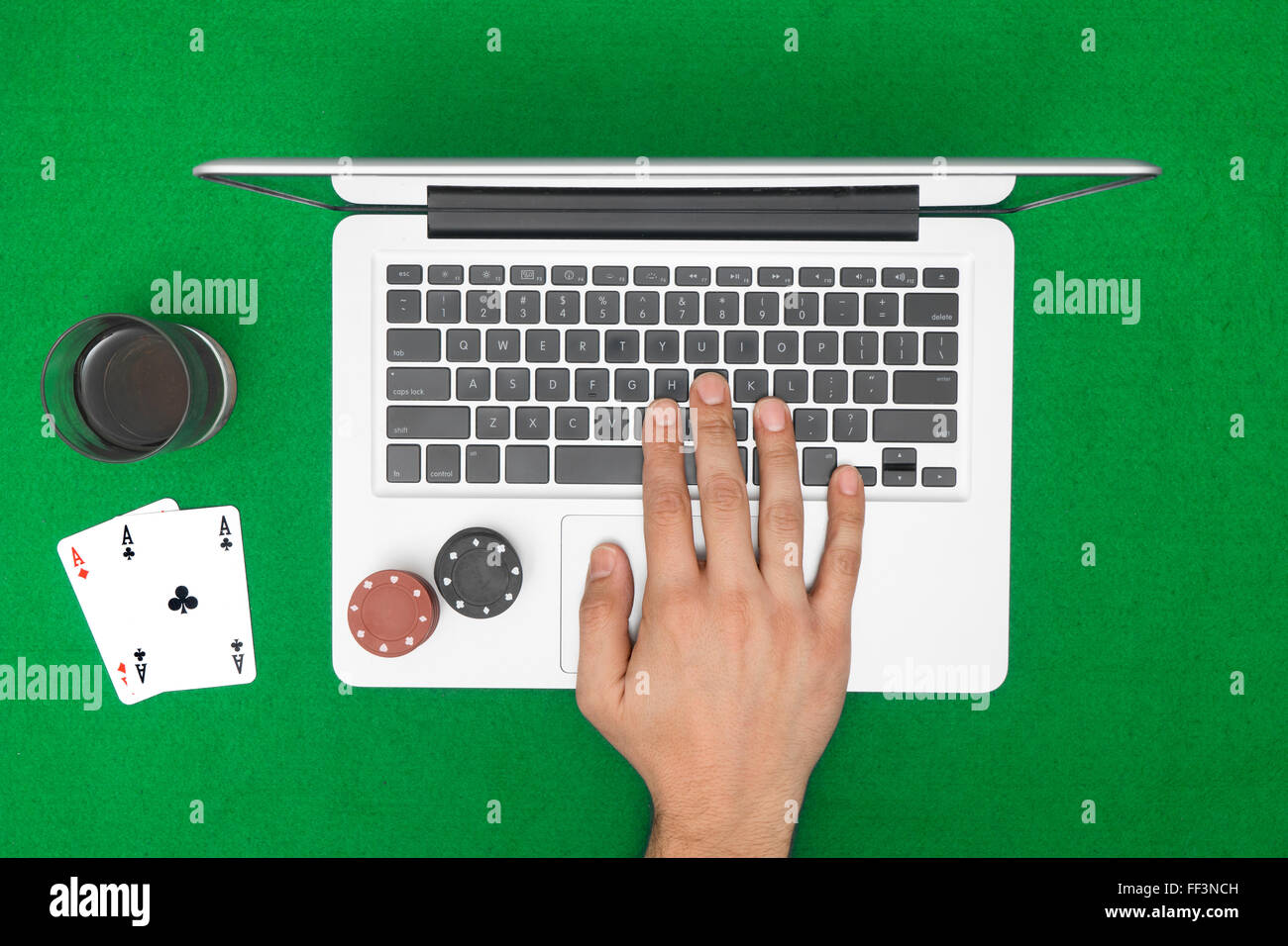 Homme jouant au poker en ligne avec un ordinateur portable sur une table verte avec des frites, vue du dessus Banque D'Images