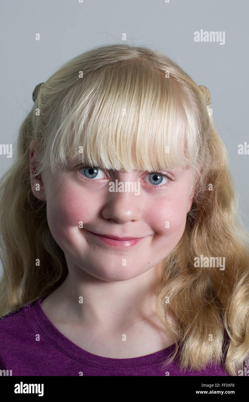 Portrait d'une jeune fille blonde avec des grappes sur un fond blanc. Banque D'Images