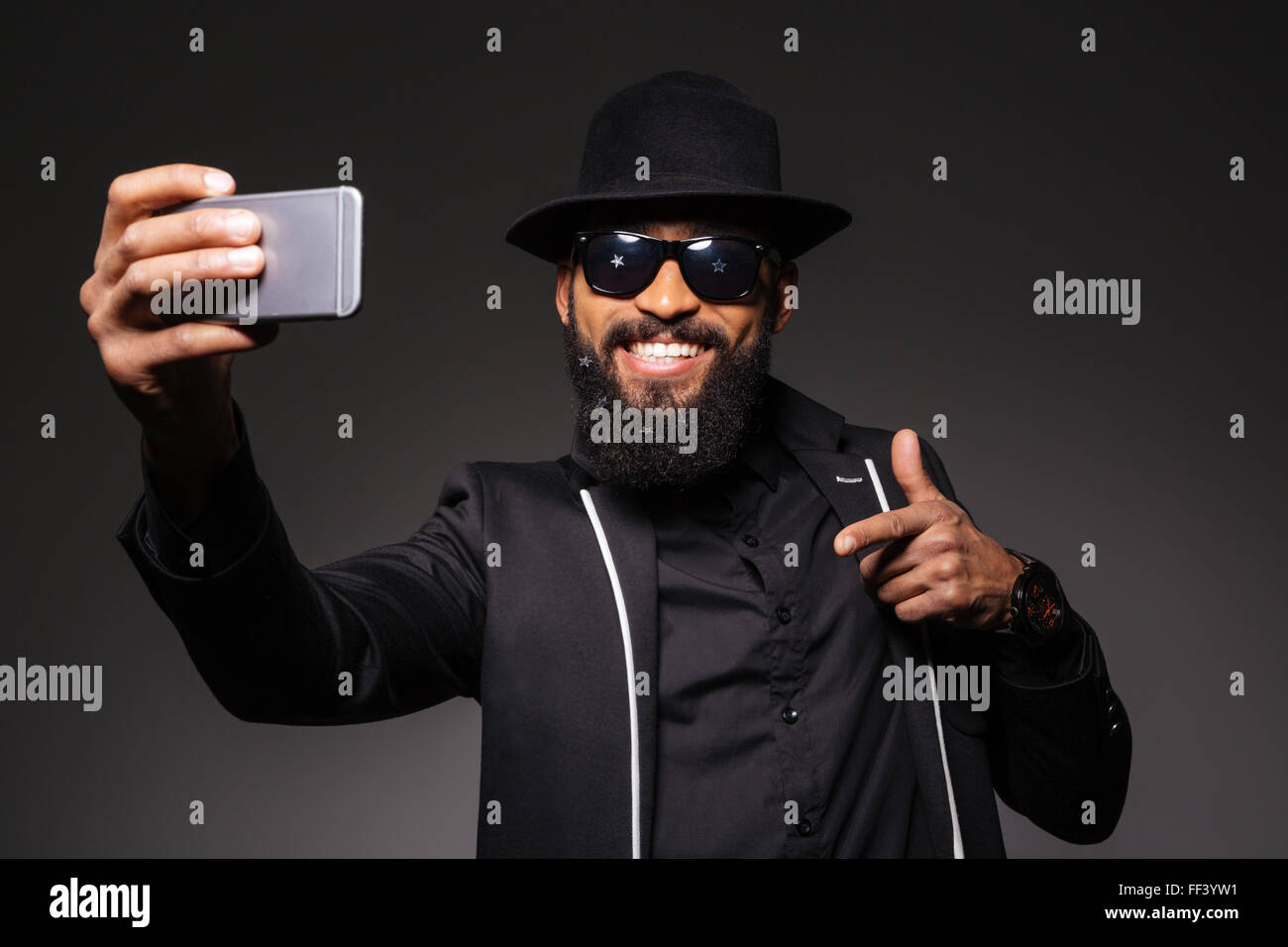 Homme heureux en tissus de mode photo selfies sur smartphone Blackberry sur fond noir Banque D'Images