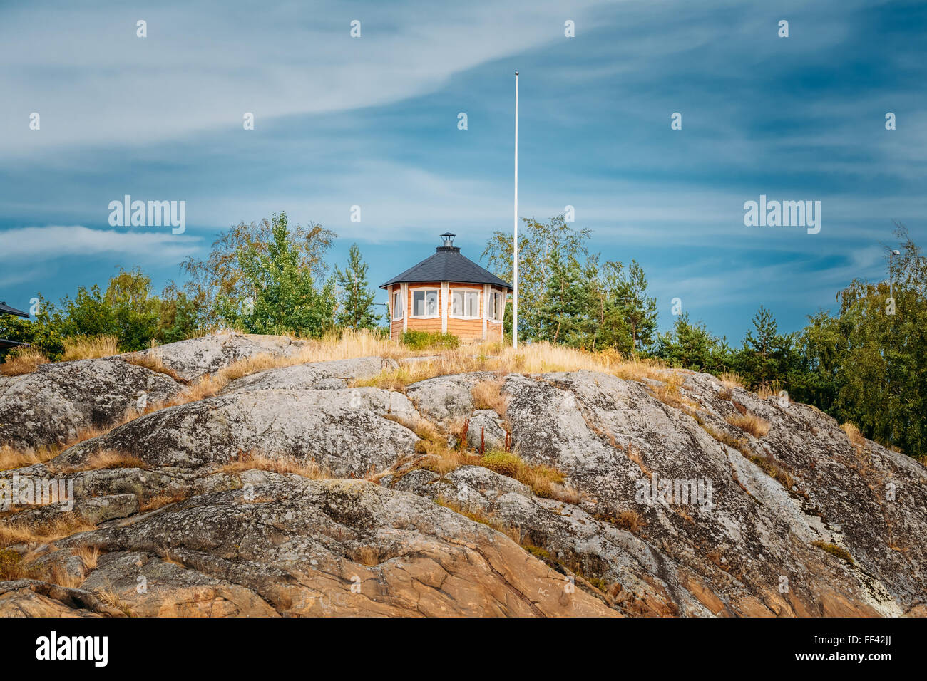 Recherche maison en bois finlandais jaune sur l'île de roche en été Banque D'Images Recherche maison en bois finlandais jaune sur l'île de roche en été Banque D'Images