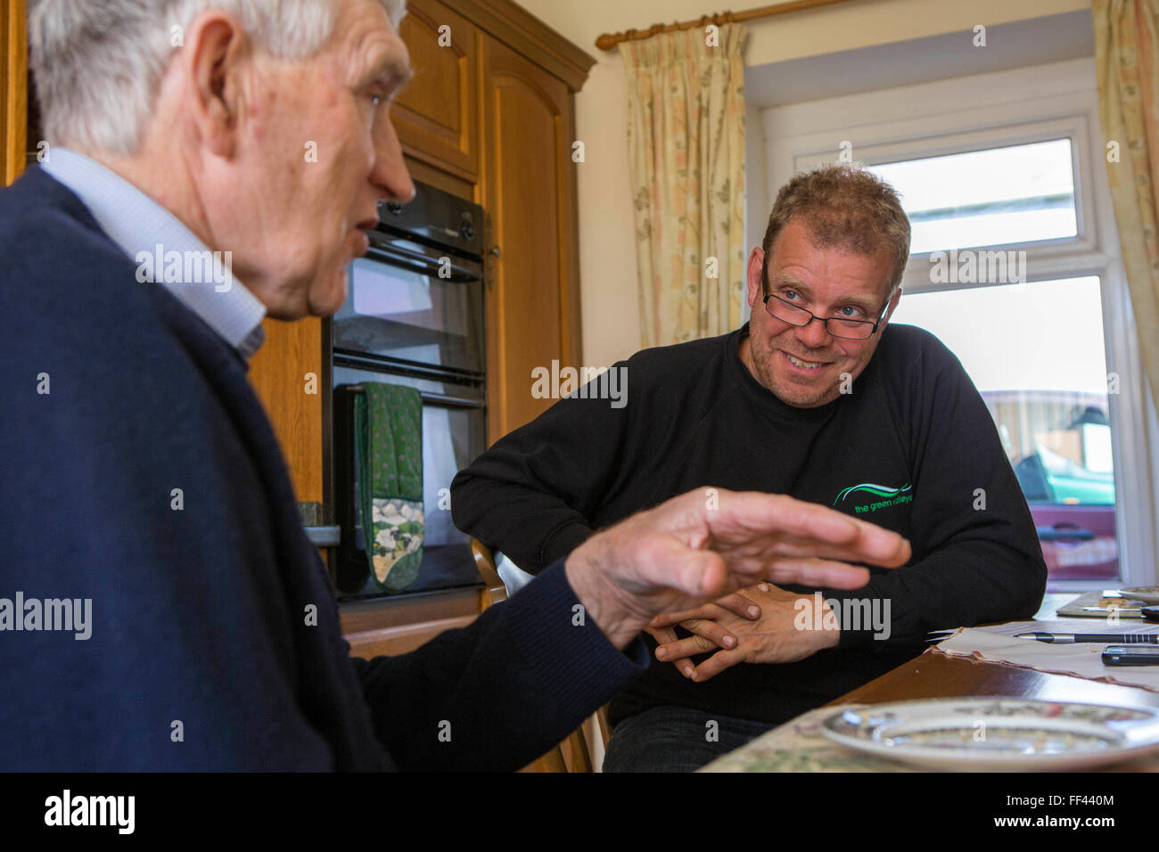 Farmer Howell Williams et Chris Blake de la Vallées vert assis dans la cuisine de la ferme de discuter la 15kW micro hydro power generator produisant de l'électricité à Abercrave ferme sur les Brecon Beacons, le Pays de Galles. Banque D'Images