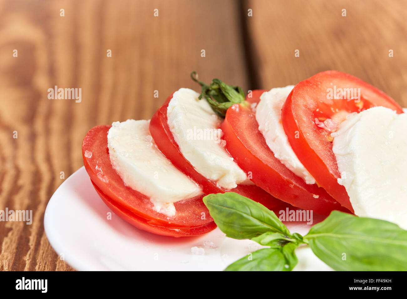 Salade de tomates mozzarella avec sel de mer sur une table en bois brun Banque D'Images