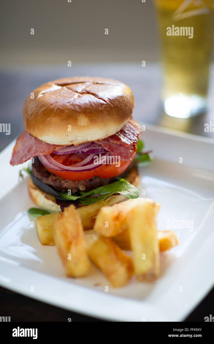 Un hamburger avec des frites et de la bière en arrière-plan Banque D'Images