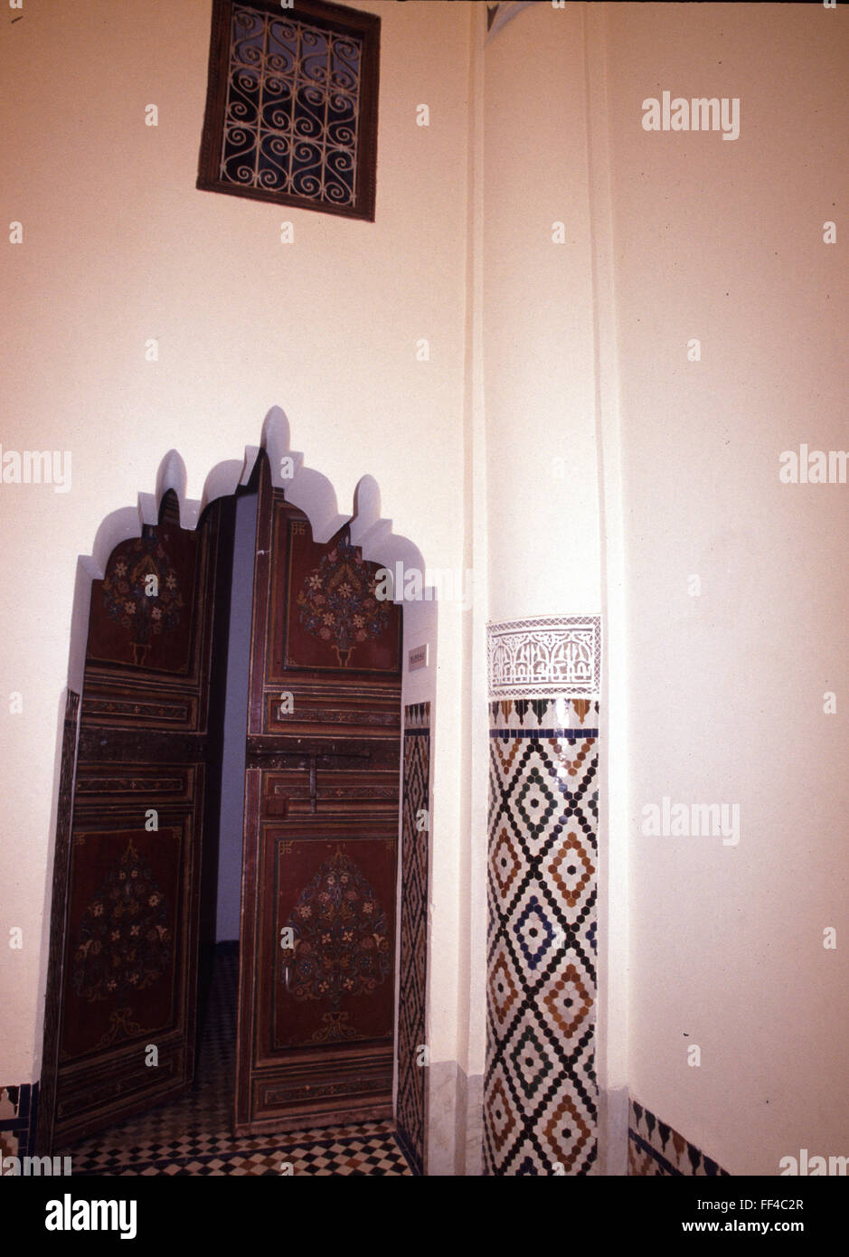 Des années 1990, porte en bois peint, vitrail et mosaïque carrelage colonne dans une mosquée au toit élevé à Marrakech, Maroc, une ville célèbre pour son pays et les portes. Banque D'Images
