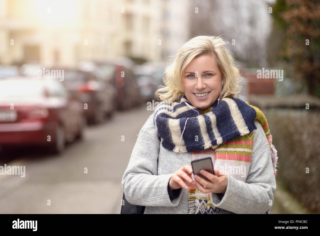 Jolie femme dans son contrôle permanent de mode d'hiver pour téléphone mobile des messages ou faire un appel dans une rue urbaine, Close up Banque D'Images