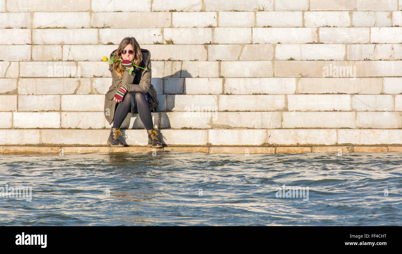 Fille assise à la rive du fleuve à l'autre côté de la rivière Banque D'Images