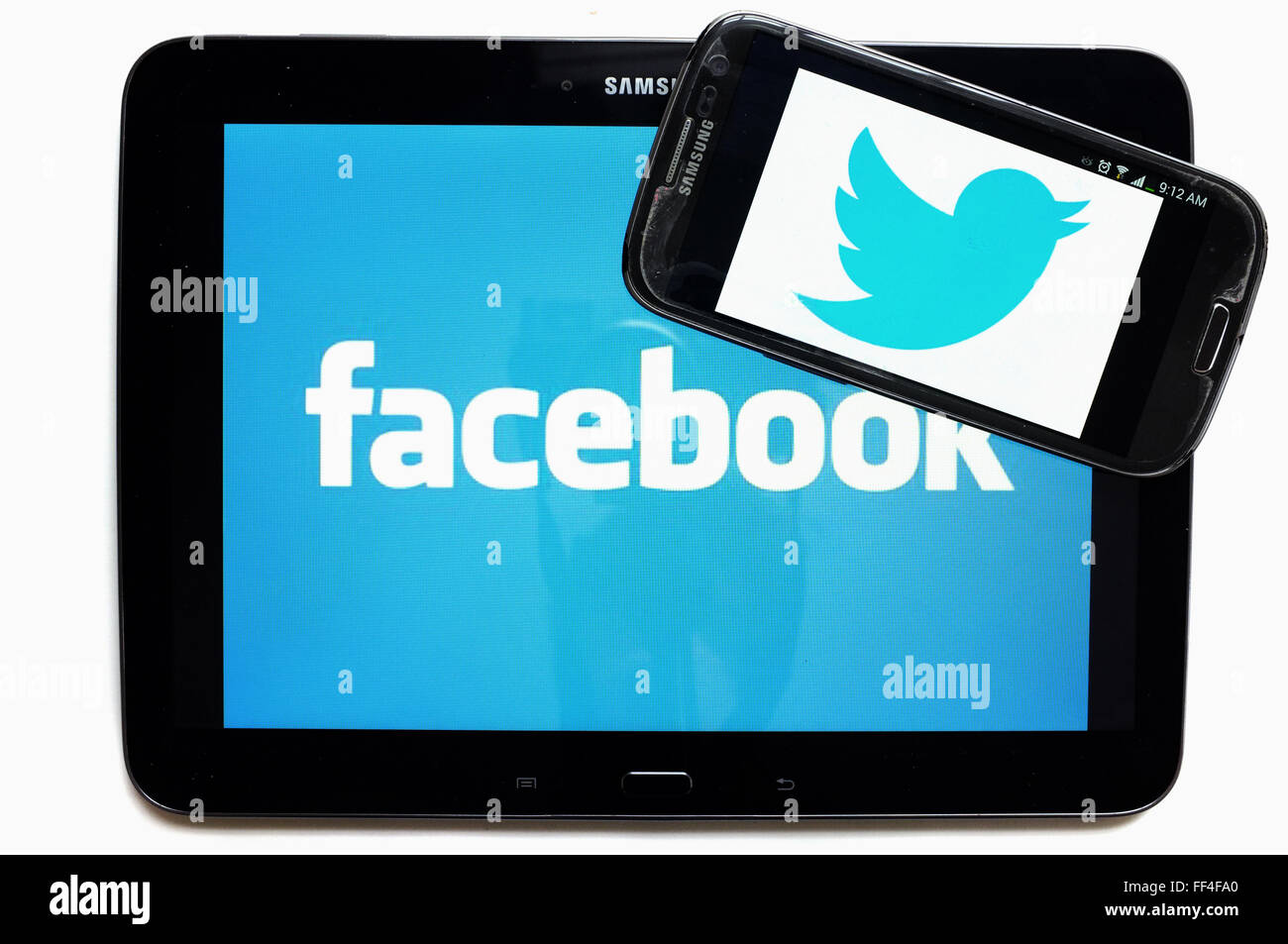 Le logo de Twitter et Facebook sur un smartphone sur une tablette photographié sur un fond blanc. Banque D'Images