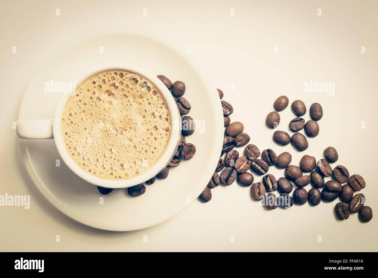 Délicieux petit déjeuner tasse de café Vue de dessus avec de la mousse et de haricots grillés, décoration vintage filtre. Chemin de détourage inclus. Banque D'Images