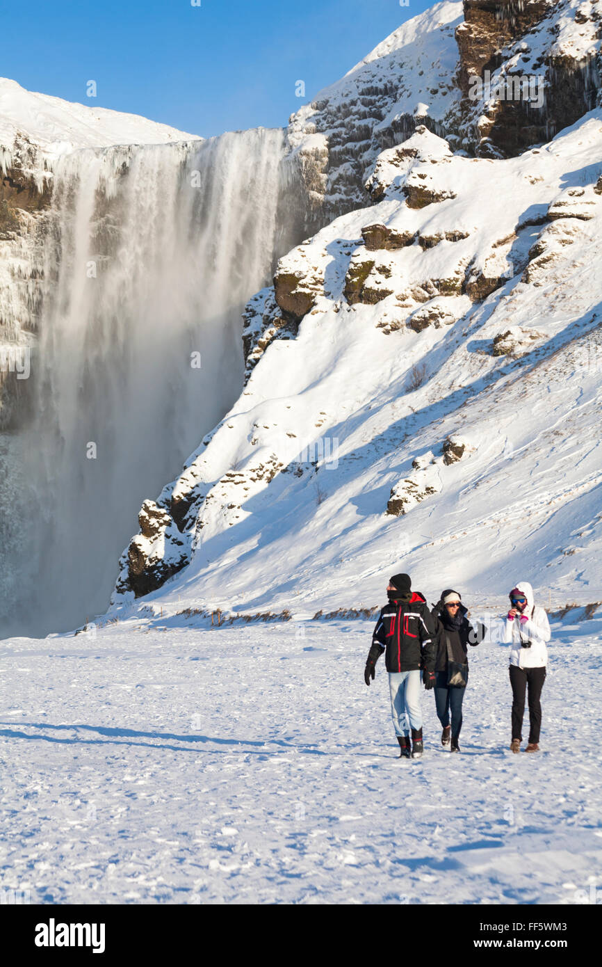 Touristes à la chute d'eau de Skogafoss, en Islande du Sud en janvier avec des icules congelés Banque D'Images