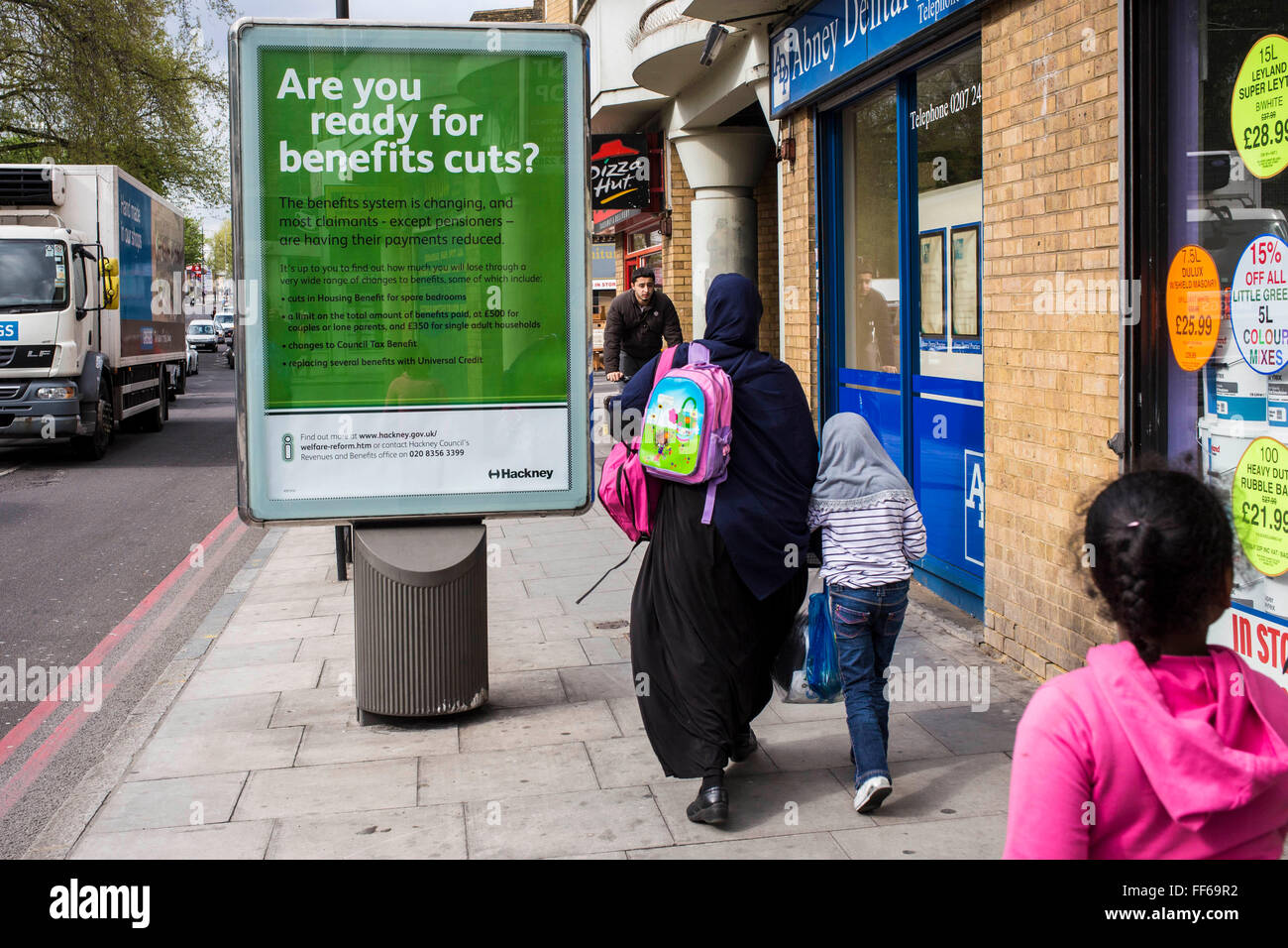 Une famille musulmane devant une affiche d'information à partir de Hackney demander : "Êtes-vous prêt à des prestations d'impôts ?" sur une route très fréquentée à Stoke Newington, Hackney, Londres, Royaume-Uni. Banque D'Images