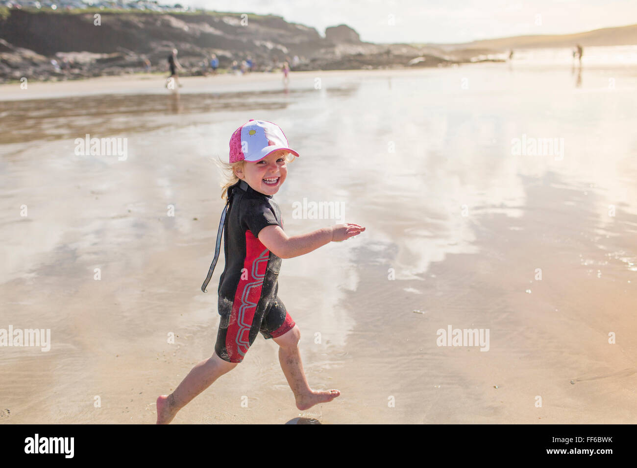 Un enfant dans une combinaison isothermique running on sand Banque D'Images