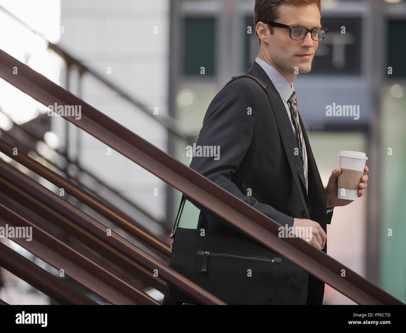 Une journée de travail. Un homme d'affaires en costume et cravate travail walking down steps tenant une tasse de café. Banque D'Images