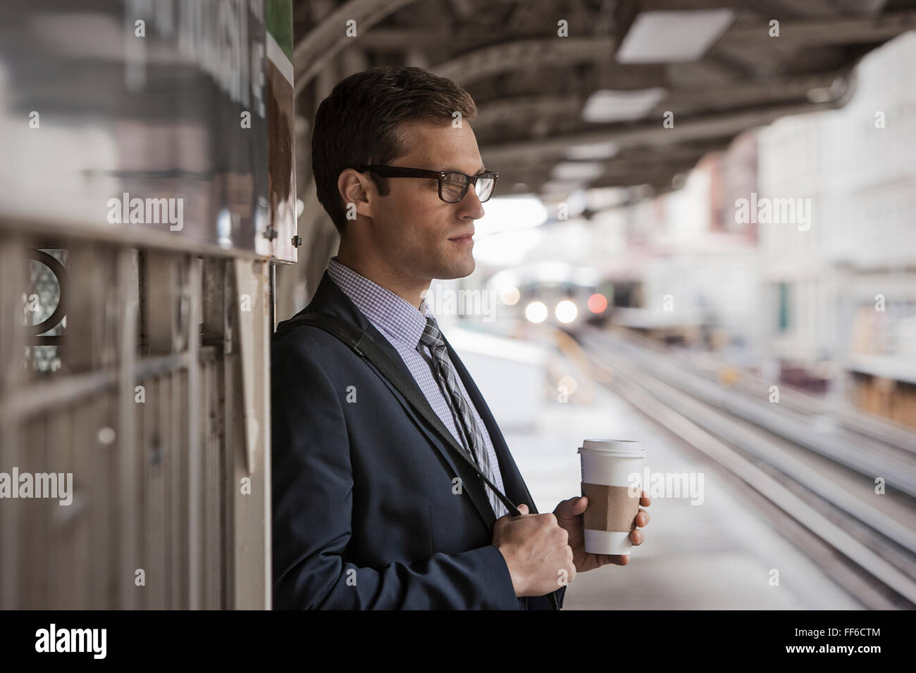 Une journée de travail. Un homme d'affaires en costume et cravate de travail tenant une tasse de café sur une plate-forme ferroviaire. Banque D'Images