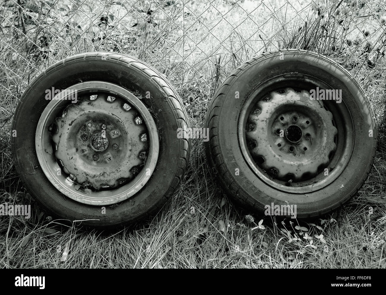 Deux vieux pneus appuyé contre une clôture grillagée Banque D'Images