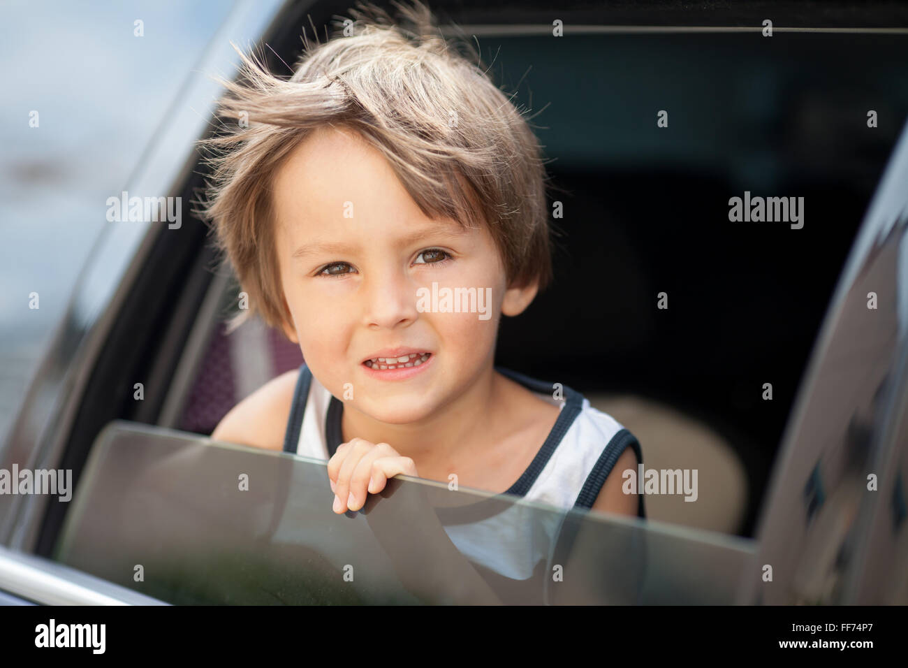 Mignon petit enfant, garçon, regardant par la fenêtre d'une voiture, smiling Banque D'Images