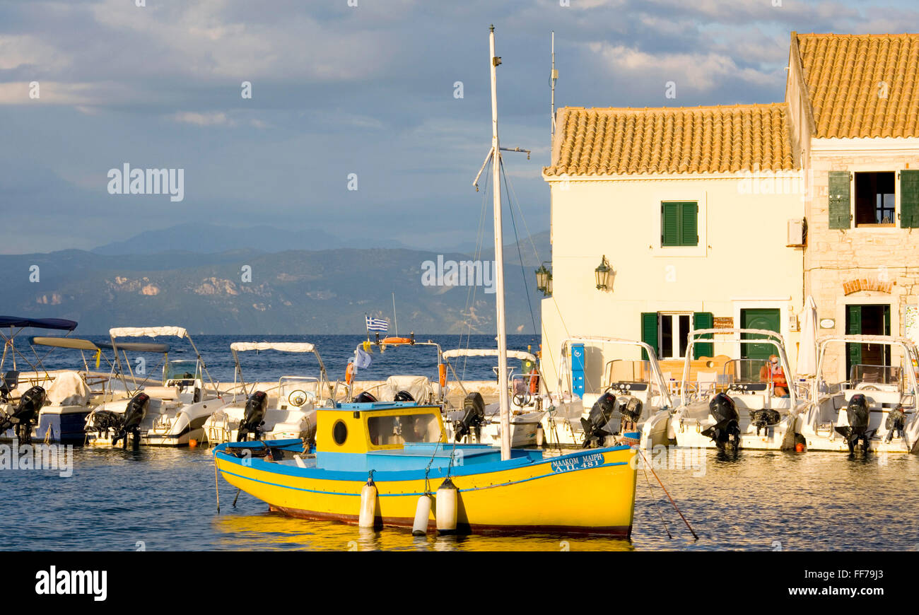Loggos, Paxos, îles Ioniennes, Grèce. Bateaux dans le port éclairé par le soleil couchant. Banque D'Images