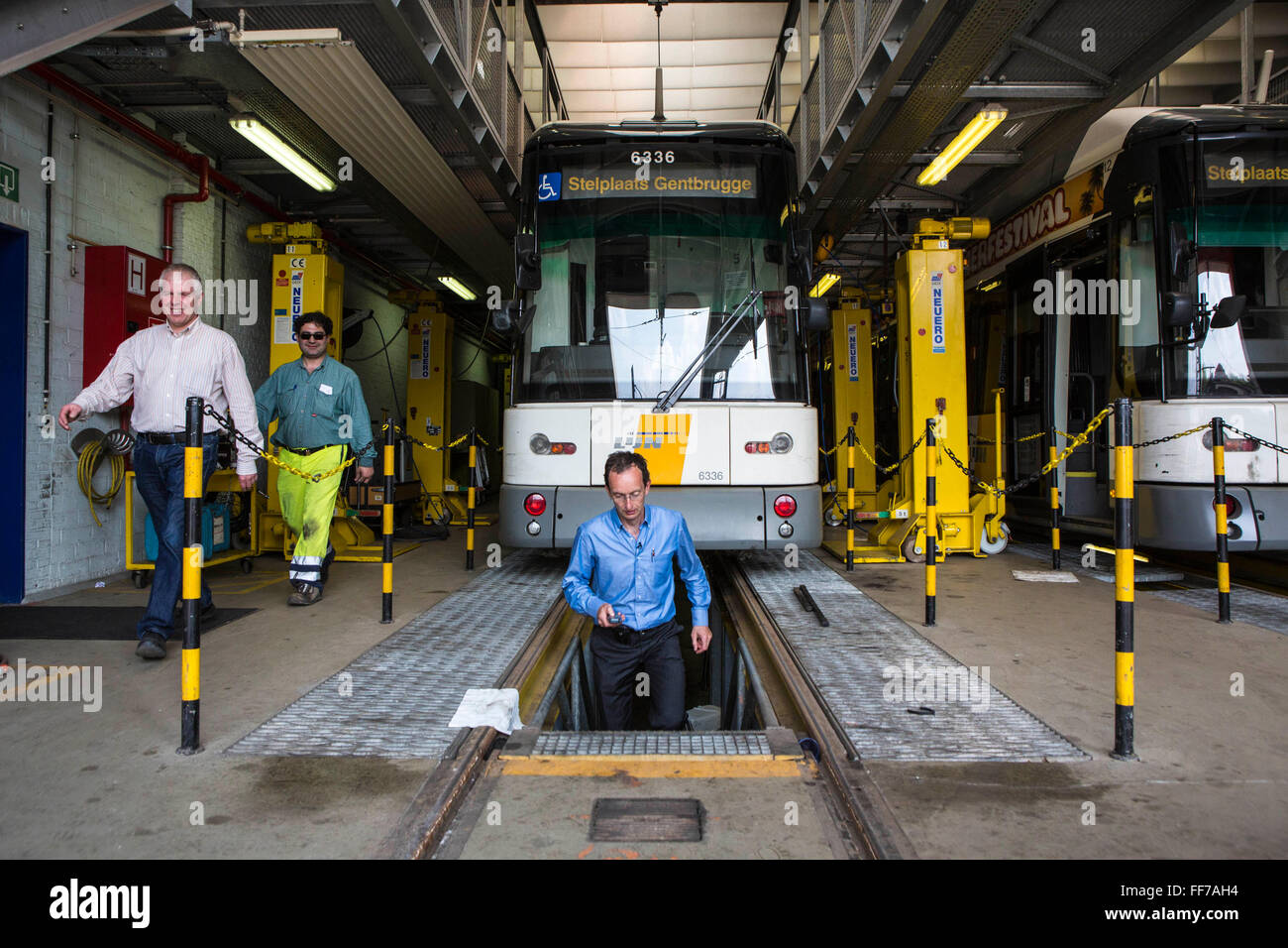 Patrick de Boeuf, chef de la direction de De Lijn, à quelques pas de la fosse zone de l'atelier sous un tramway moderne deux hommes à pied le long du côté le tram au dépôt à Gentbrugge, Gand, Belgique. Les tramways ont été modernisés pour réduire la consommation d'électricité et a gagné une bourse de voyage durable de prix Ashden. Banque D'Images