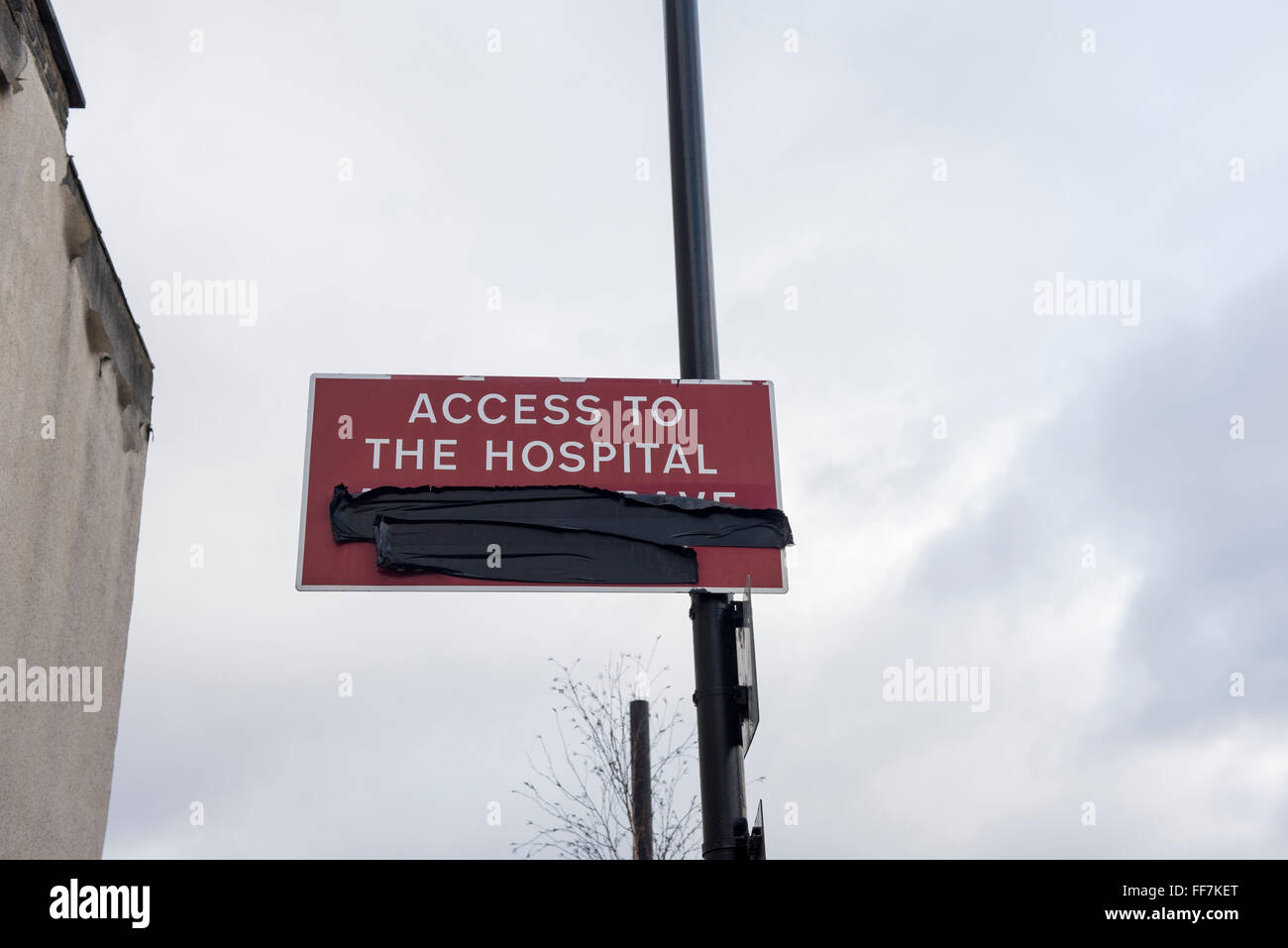 'Accès à l'hôpital' enseigne à la lampe se tiennent près de l'Hôpital Universitaire de Newham, East London, UK. Certains mots couverts avec du ruban adhésif noir Banque D'Images