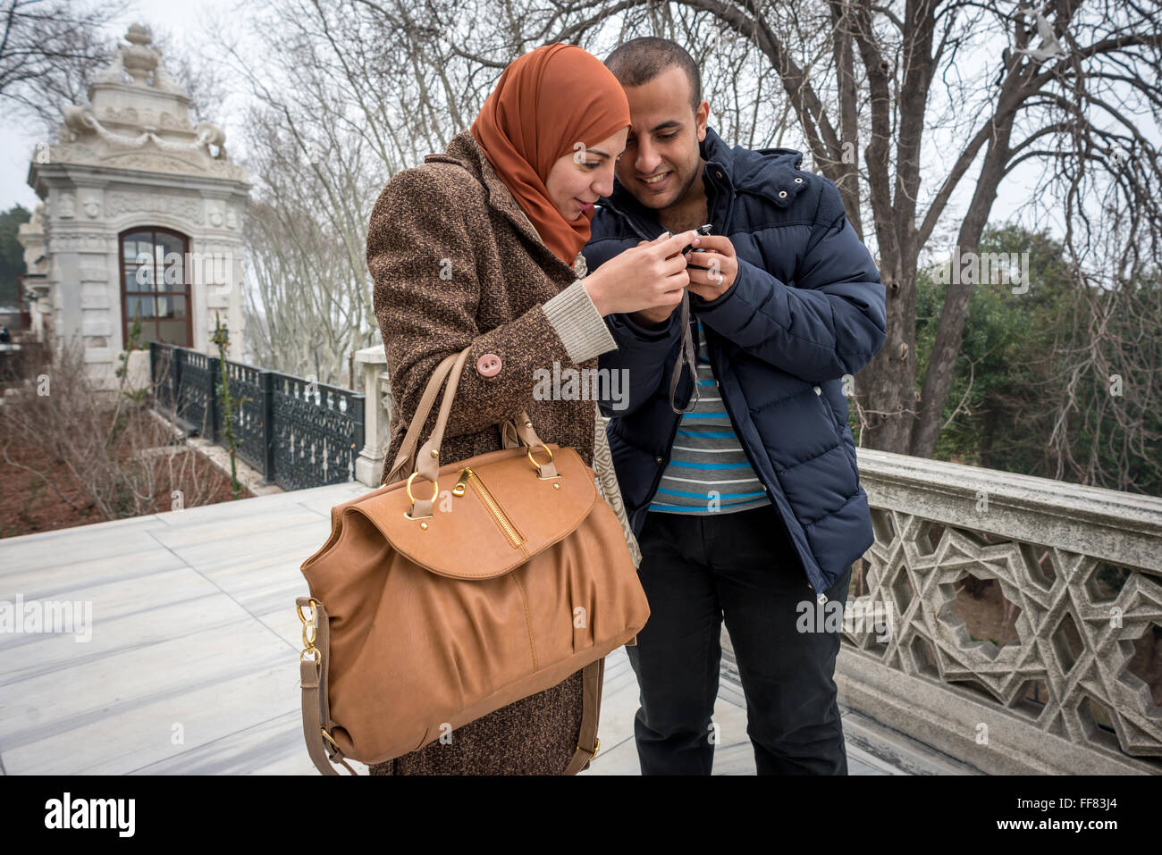 Un jeune couple vérifier vos messages téléphoniques et photos sur leur appareil intelligent, dans le parc du palais de Topkapi à Istanbul, Turquie. Banque D'Images