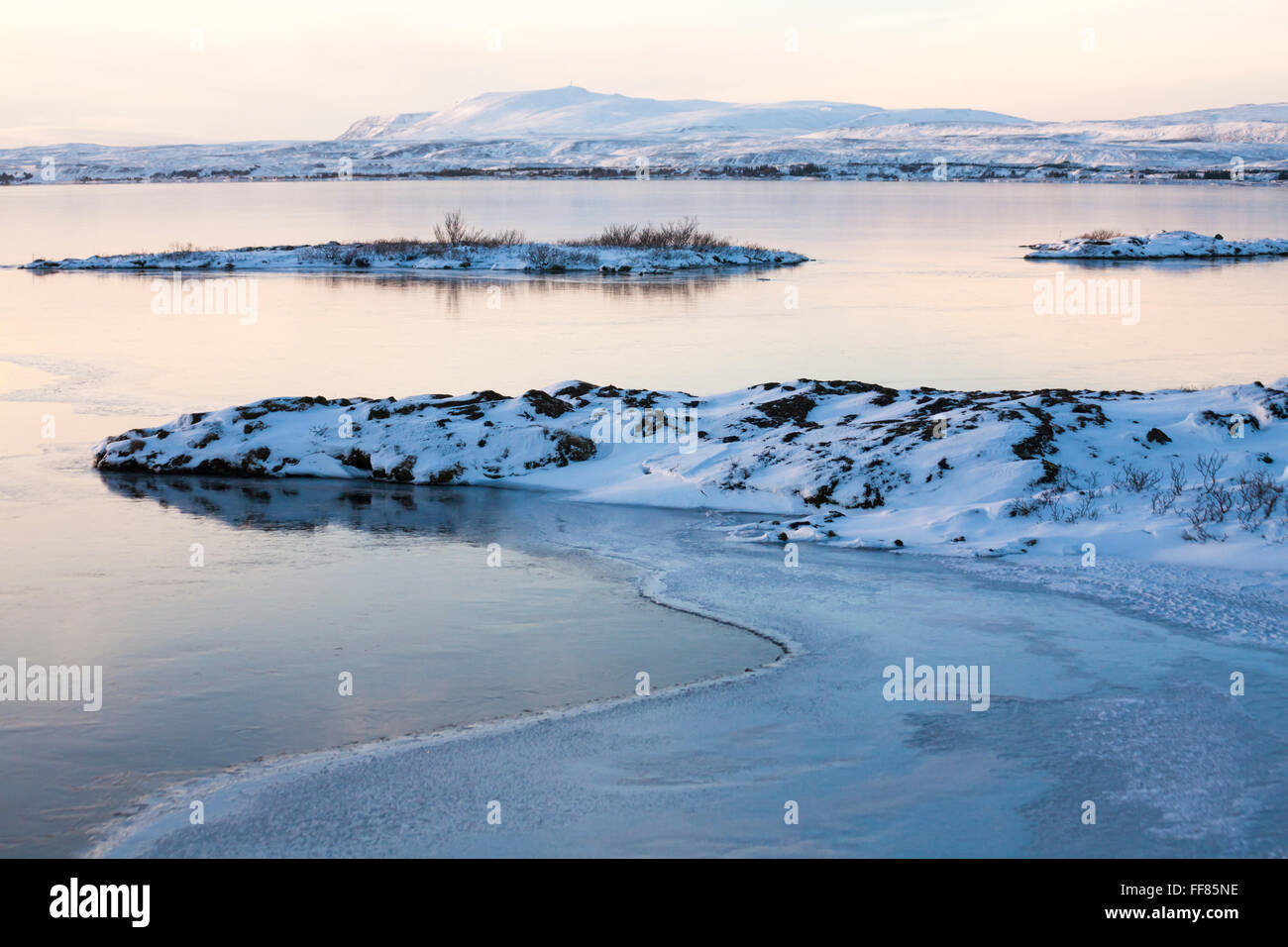 L'eau congelée au coucher du soleil avec les montagnes couvertes de neige dans la distance en Islande en Janvier Banque D'Images