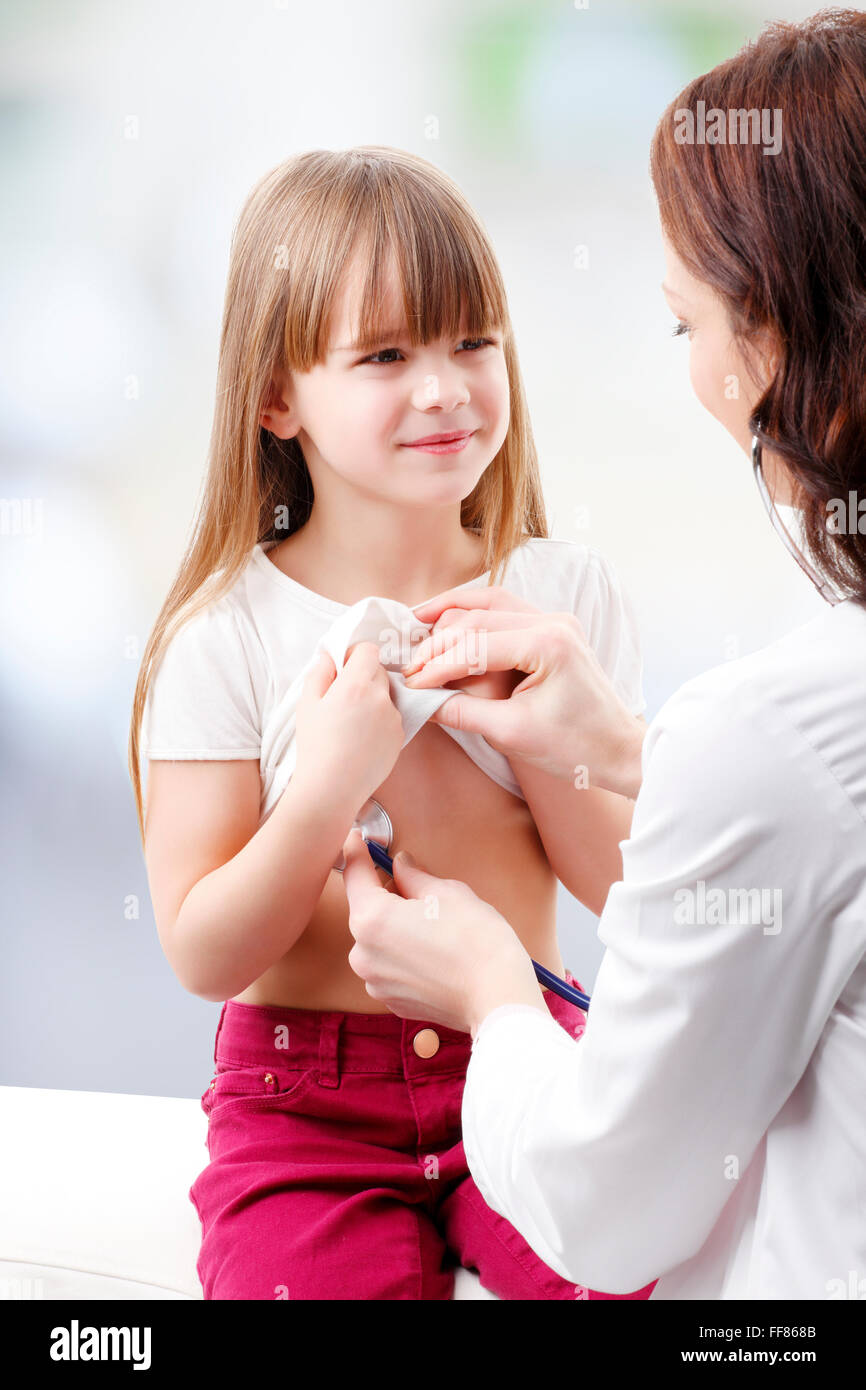 Femme médecin écoute brisa le coeur de l'enfant d'âge préscolaire à la clinique. Banque D'Images