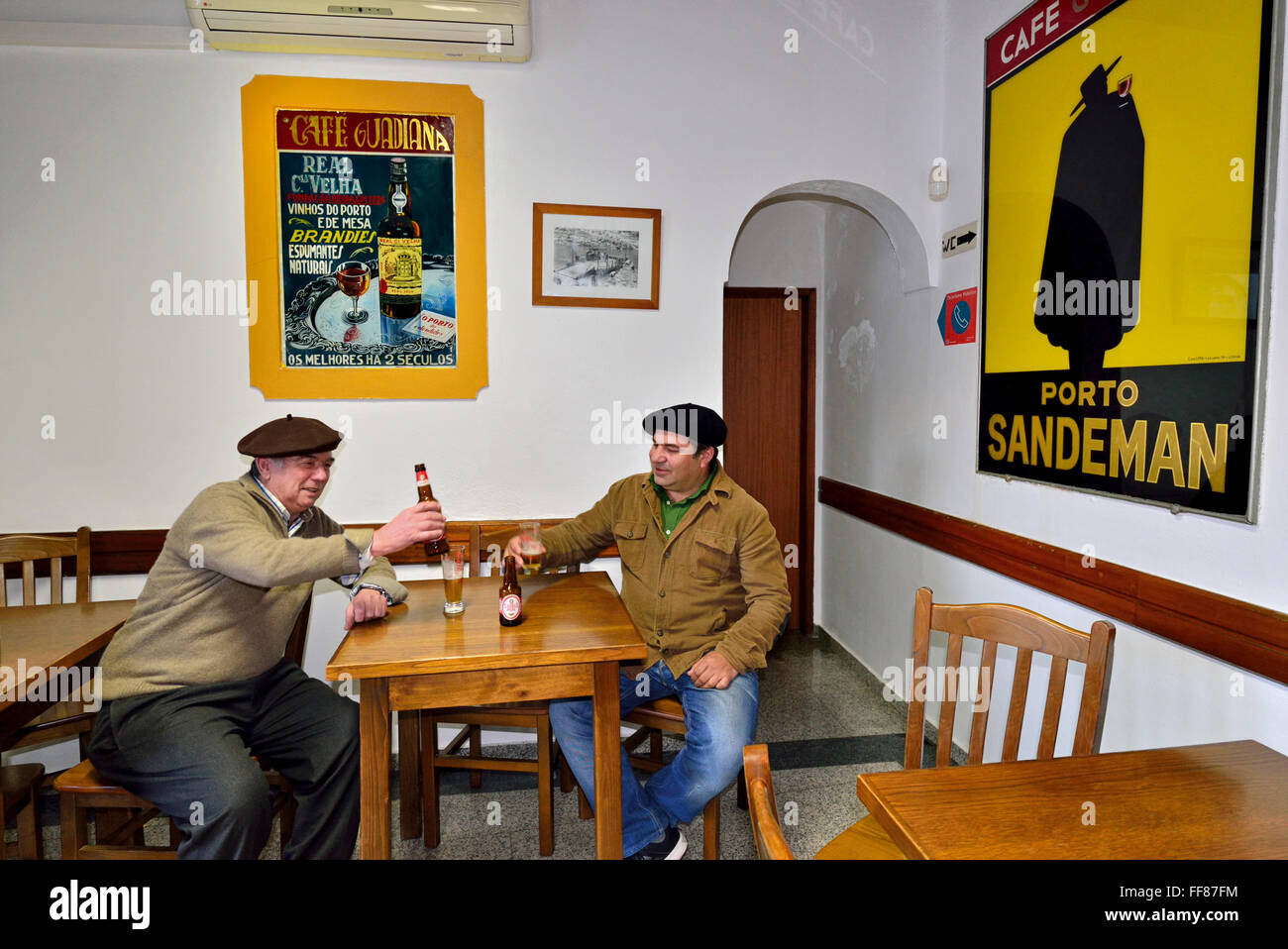 Le Portugal, l'Alentejo : deux hommes autochtones ayant une bière et un chat dans le café traditionnel Guadiana dans Mértola Banque D'Images