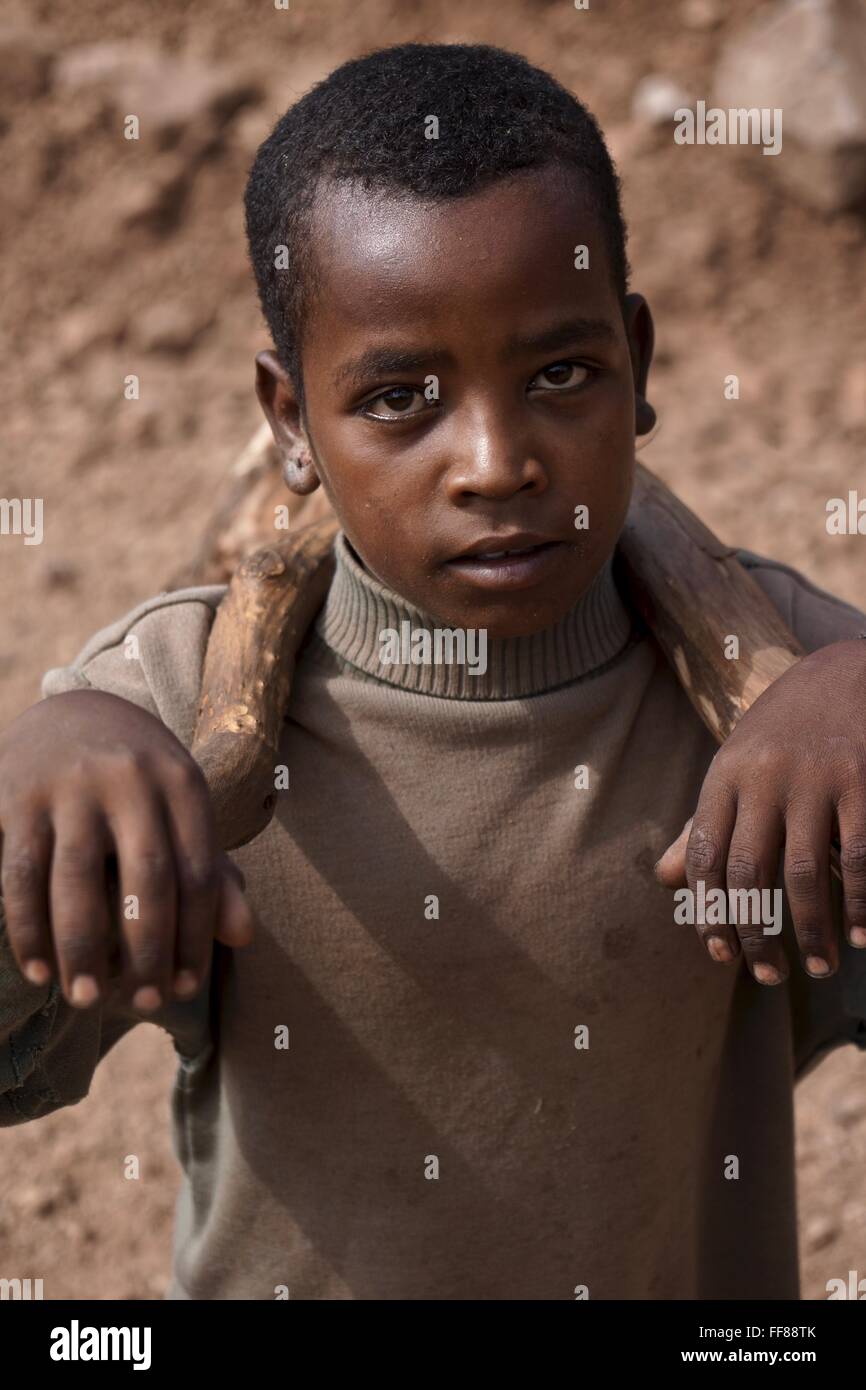 African boy carrying stick sur les épaules. Banque D'Images