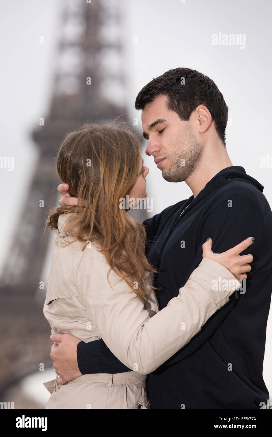 Jeune couple, man and woman standing in front of Tour Eiffel, Paris, France, à la recherche dans chaque autres des yeux, presque s'embrasser Banque D'Images