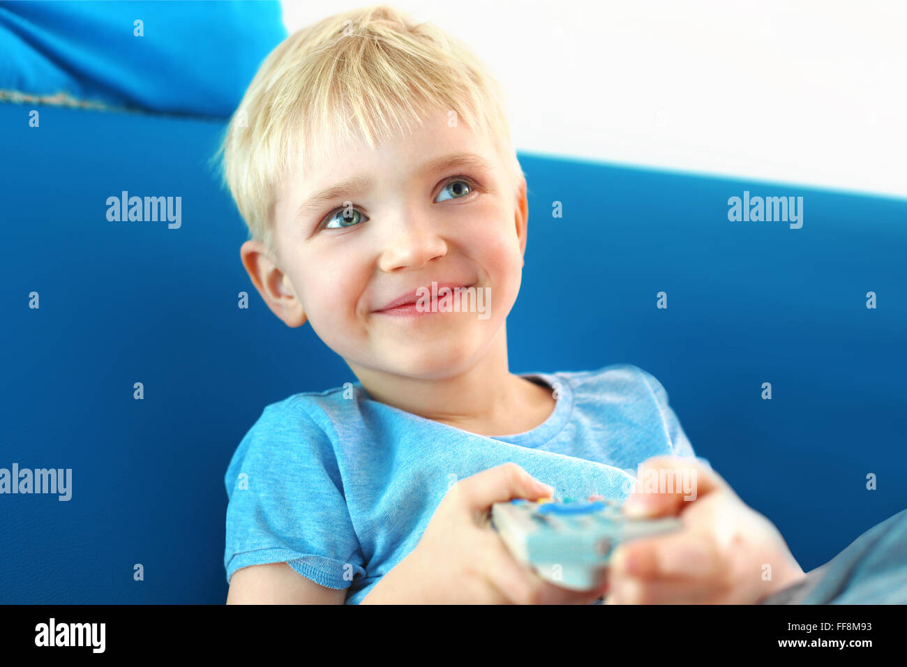 J'aime la télévision. Un enfant avec une télécommande du téléviseur. Le garçon est en train de changer le canal sur le téléviseur à l'aide de la télécommande Banque D'Images