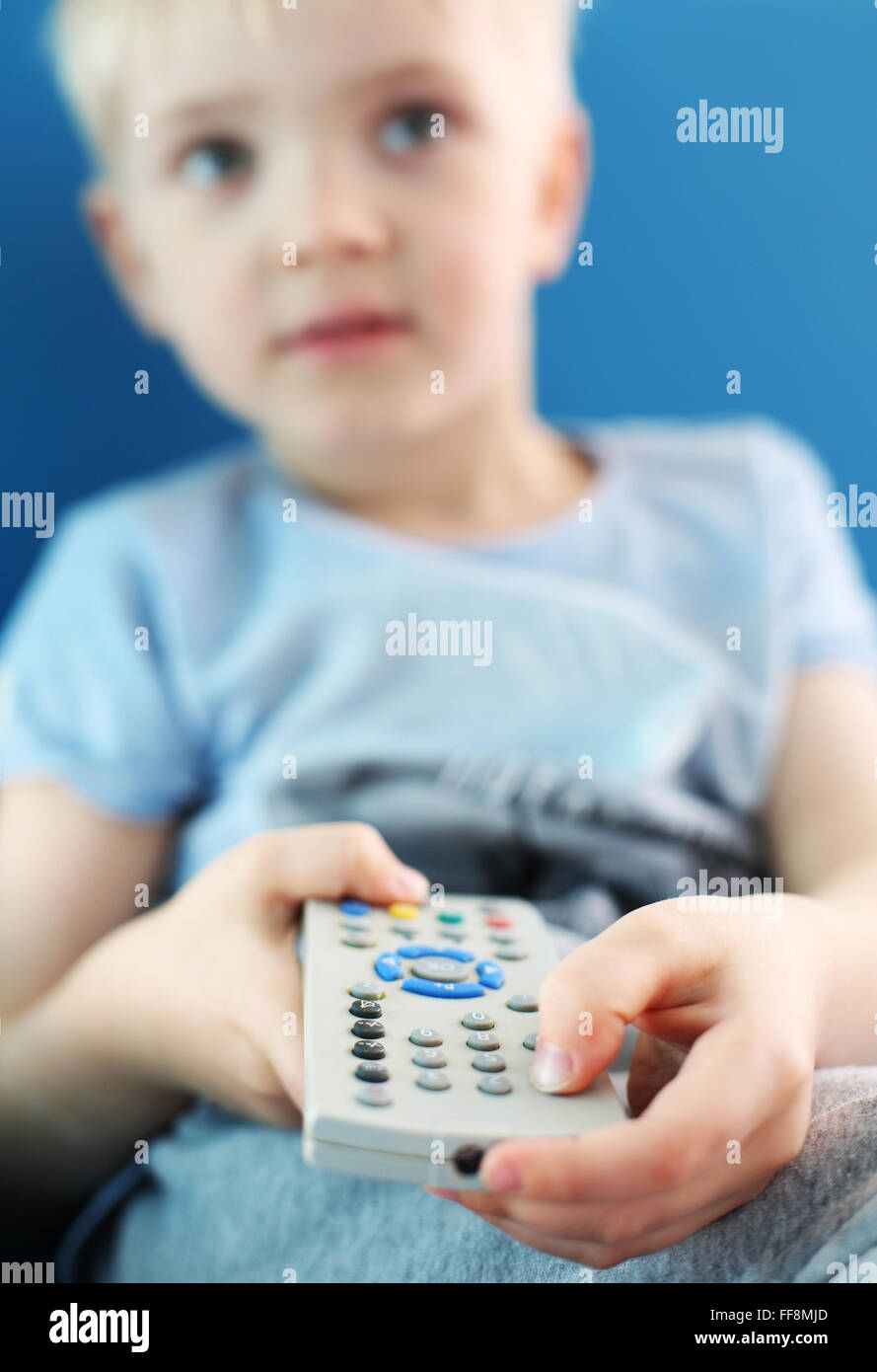 J'aime la télévision. Un enfant avec une télécommande du téléviseur. Le garçon est en train de changer le canal sur le téléviseur à l'aide de la télécommande Banque D'Images