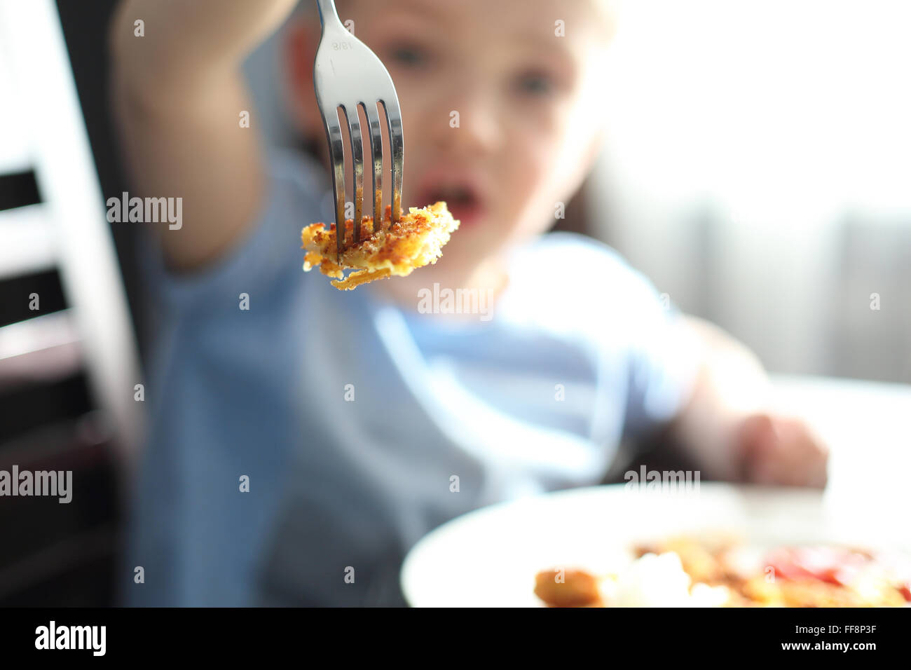 Enfant en mangeant. Le petit garçon au cours d'un repas montre chop estampillé sur une fourchette. Banque D'Images