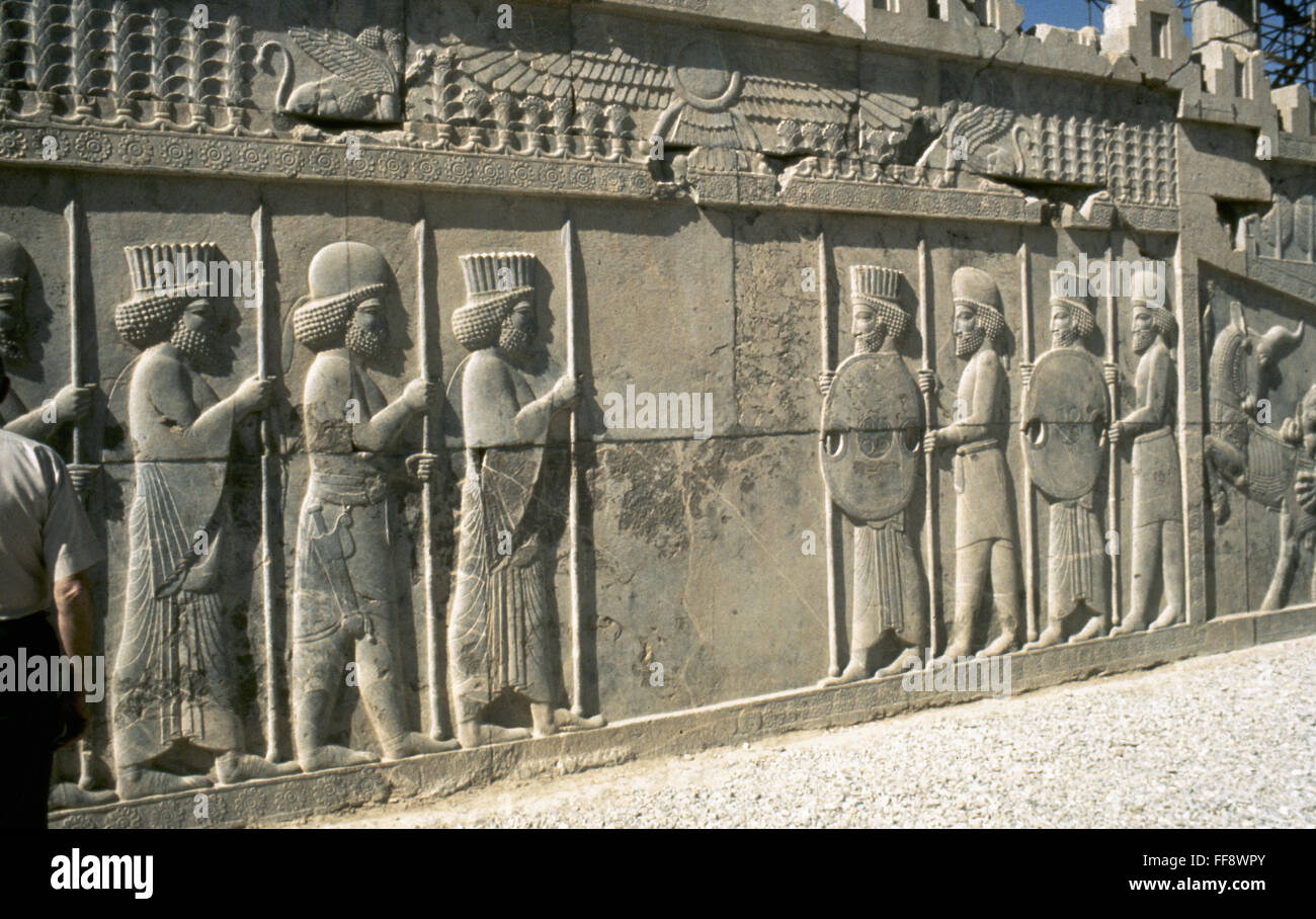 BAS-relief de Persépolis. NPersepolis /bas-relief de Mèdes (chapeaux ronds) et les Perses (chapeaux à cannelures). Au-dessus d'eux est un disque ailé symbole de Dieu Ahura Mazda. Banque D'Images