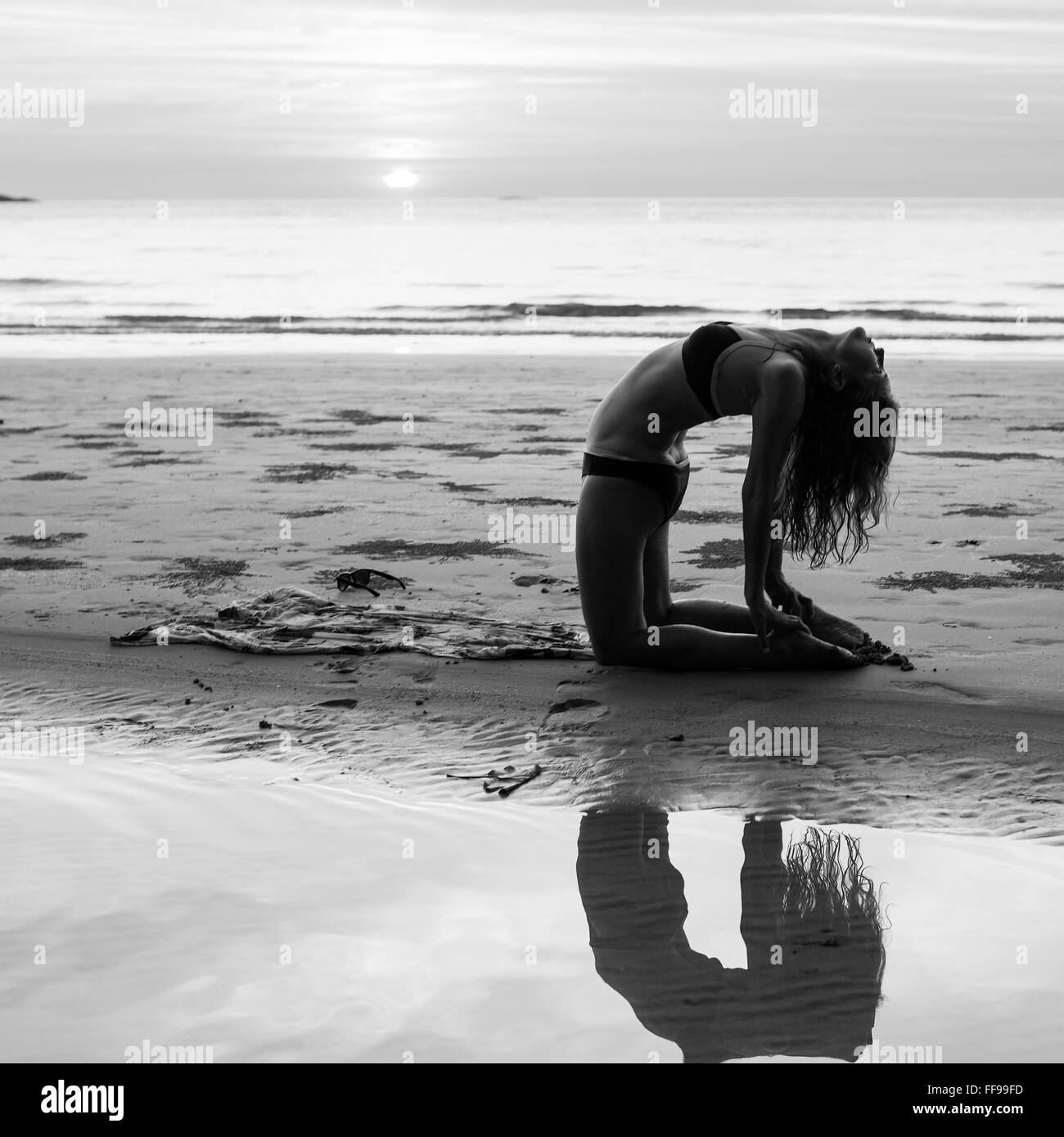 Exercices de yoga silhouette de femme sur la plage au coucher du soleil. La photographie en noir et blanc. Banque D'Images