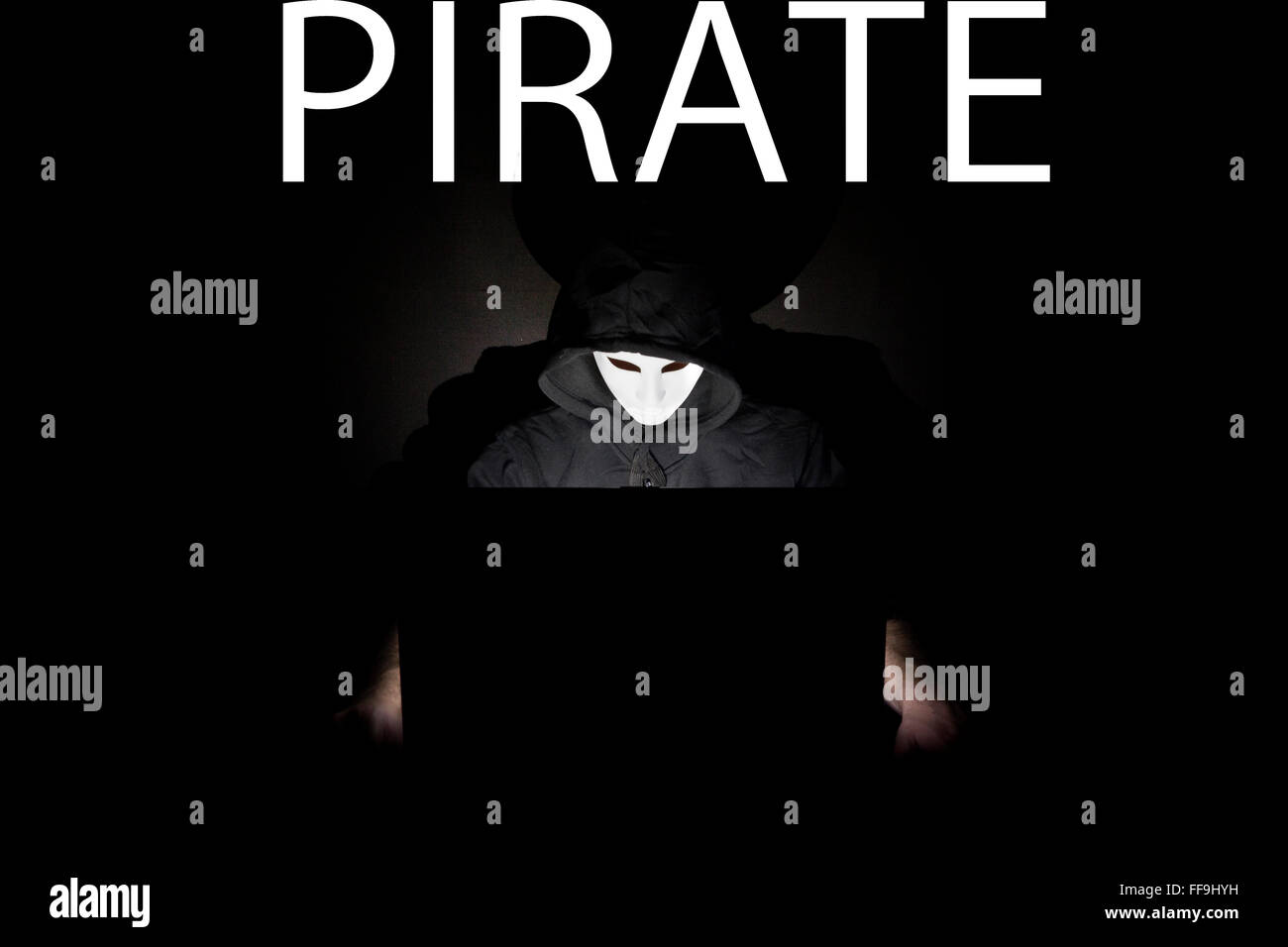 Un homme masqué à un ordinateur portable symbolisant les dangers de l'Internet. Banque D'Images