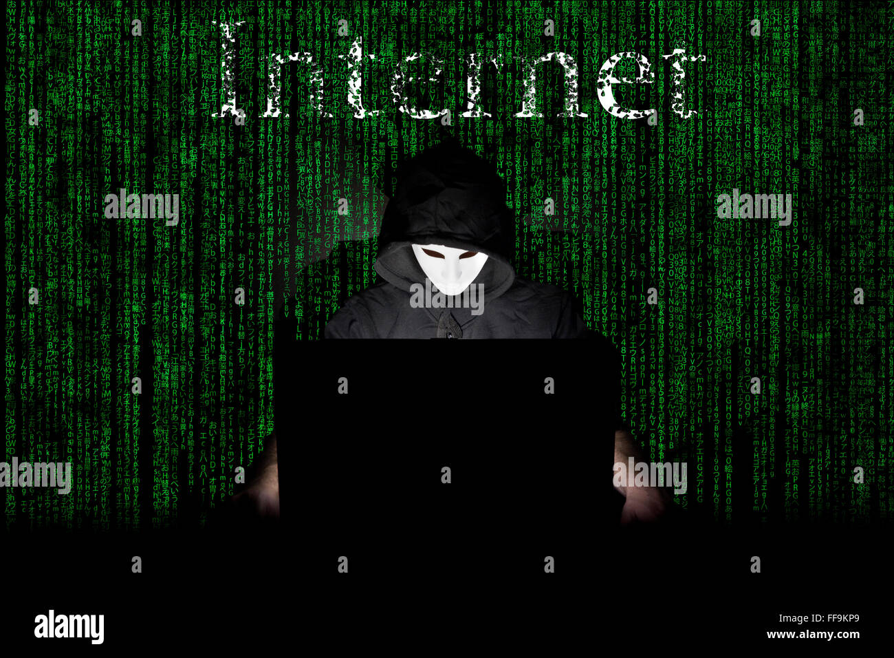 Un homme masqué à un ordinateur portable symbolisant les dangers de l'Internet. Banque D'Images