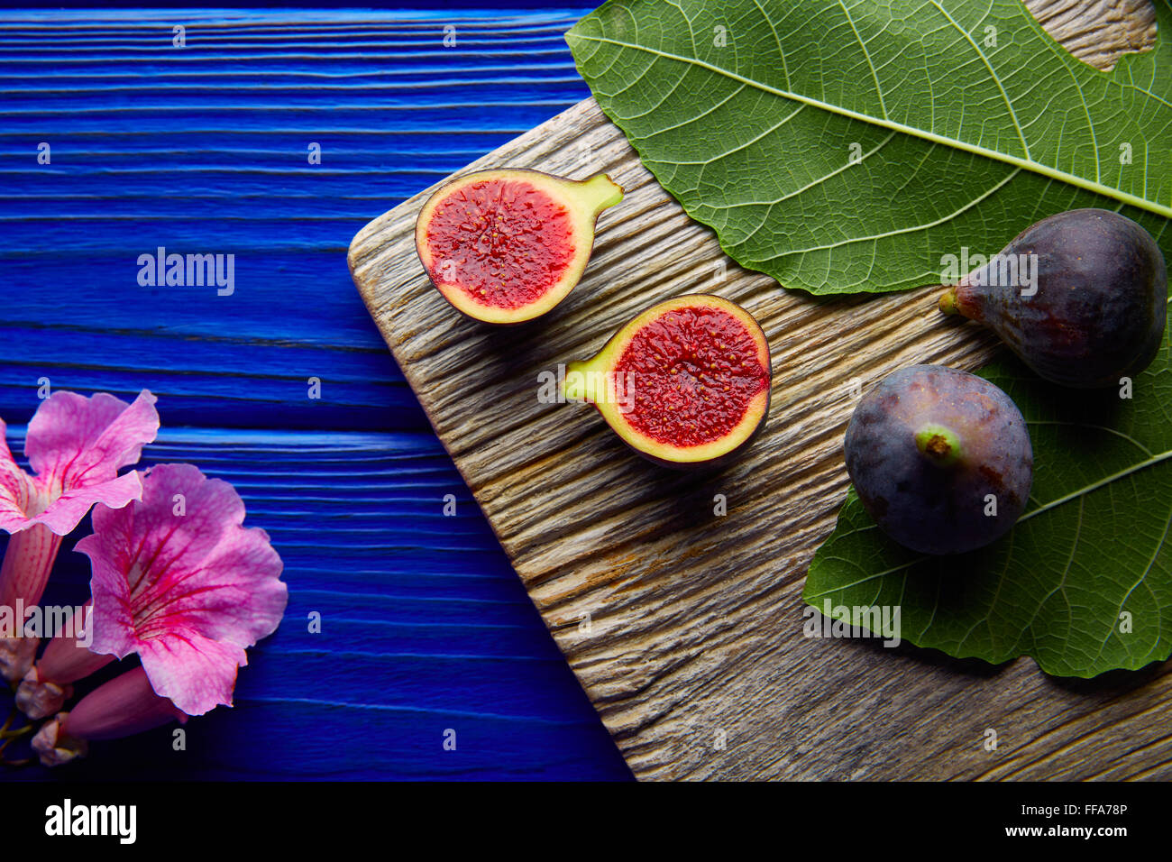 Matières premières fruits figues coupées et les feuilles de figuier sur table en bois bleu Banque D'Images