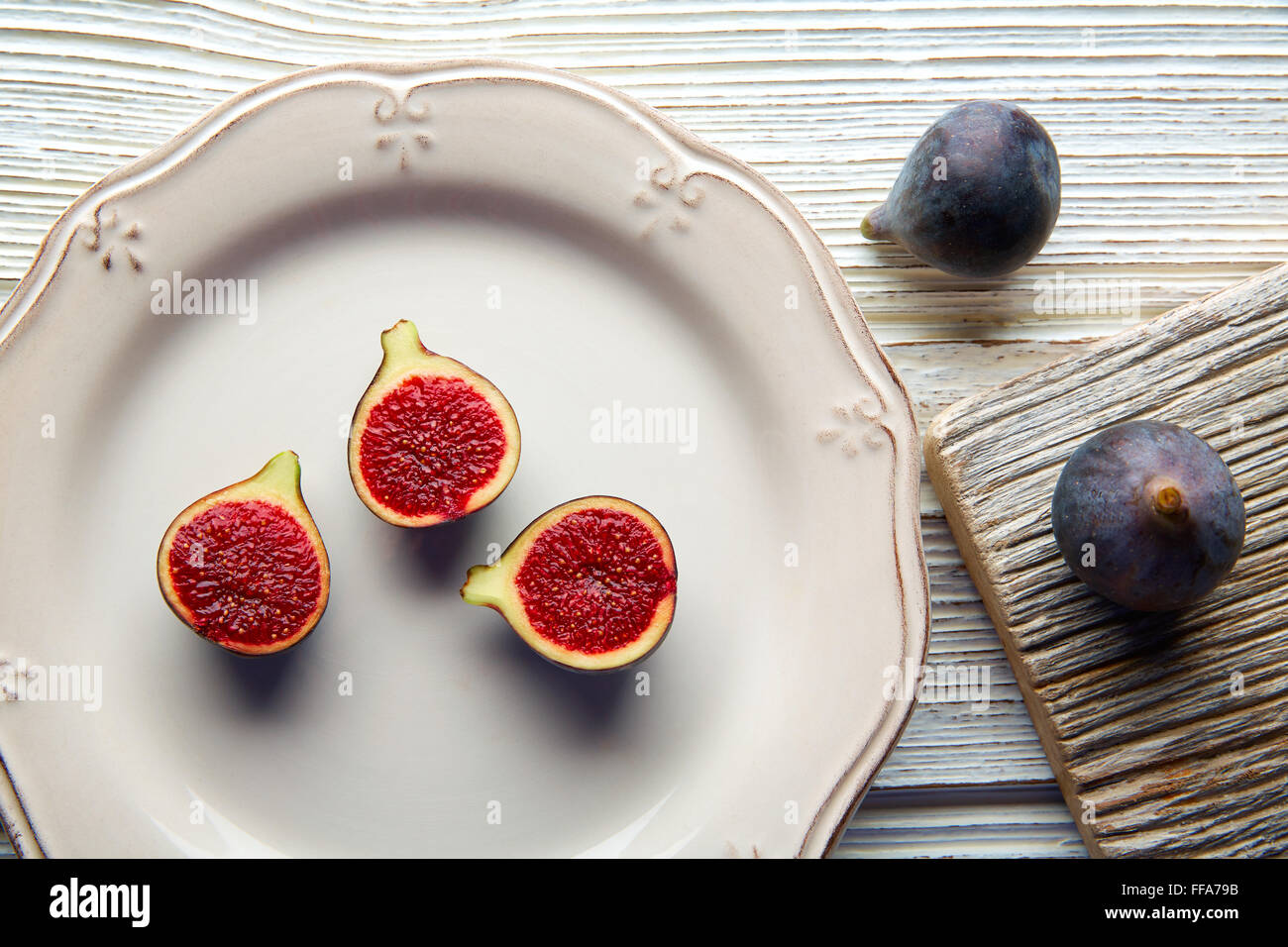 Figues matières cutted fig fruits sur plaque blanche et table en bois Banque D'Images