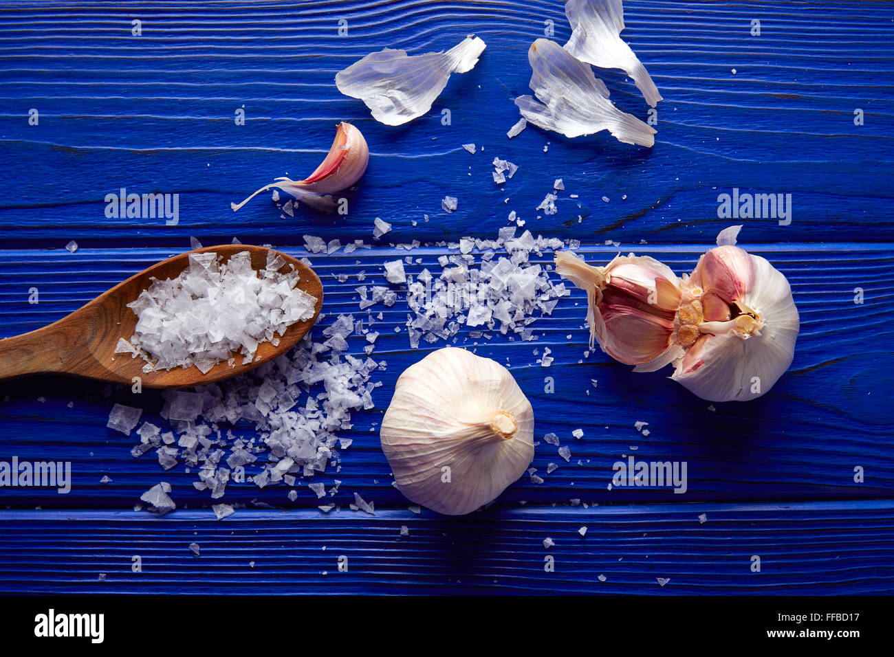 L'ail et le sel répandu sur une table en bois bleu avec composition occasionnels Banque D'Images