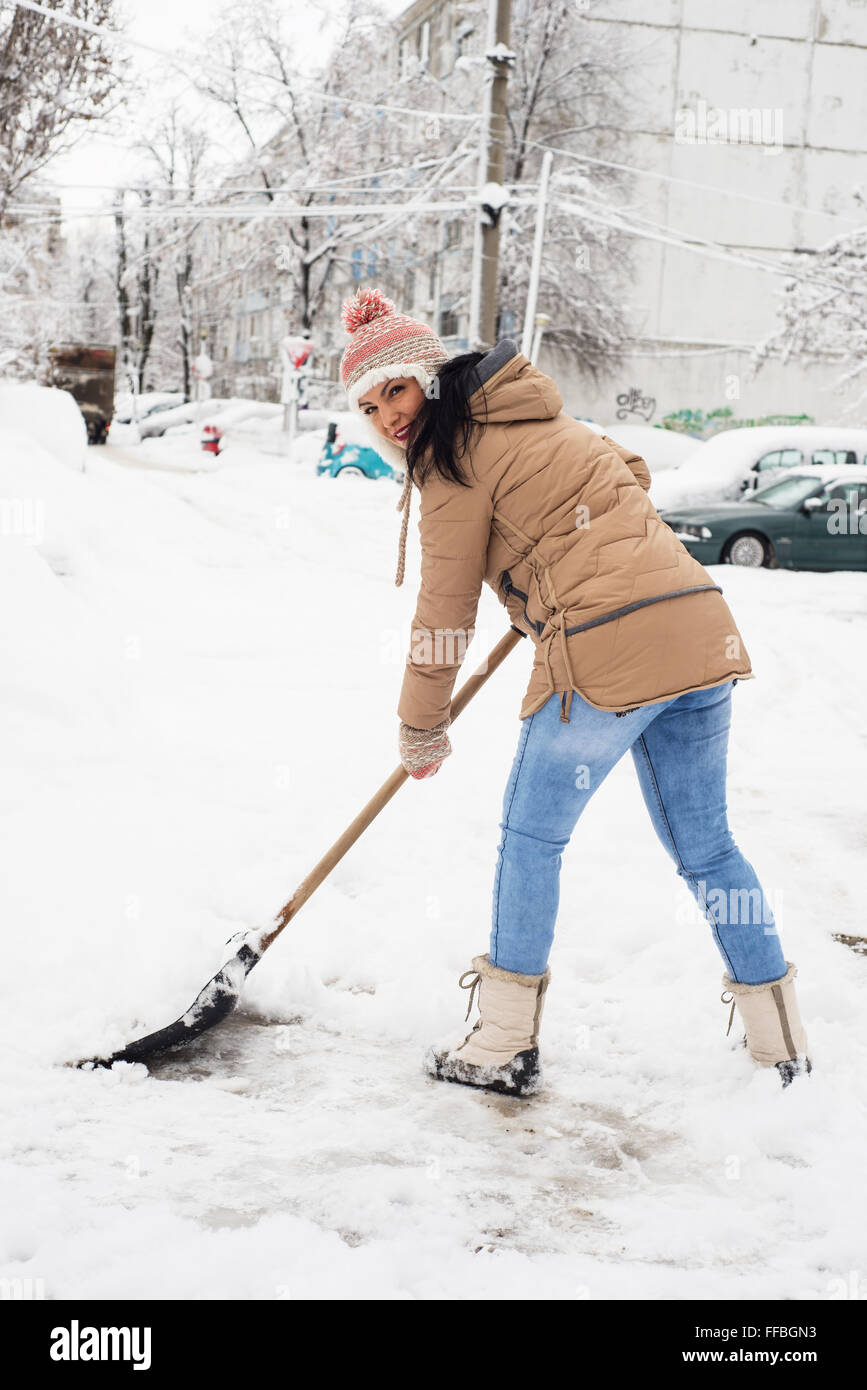 Femme de pelleter de la neige dans le stationnement à jour froid en hiver Banque D'Images