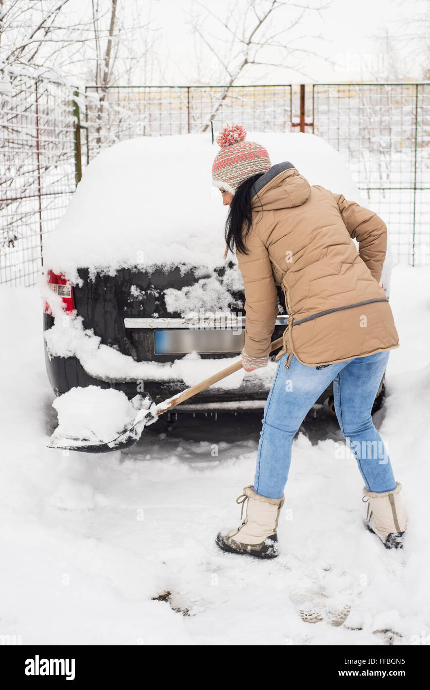 Nettoyage femme neige autour de voiture et prendre un chemin Banque D'Images